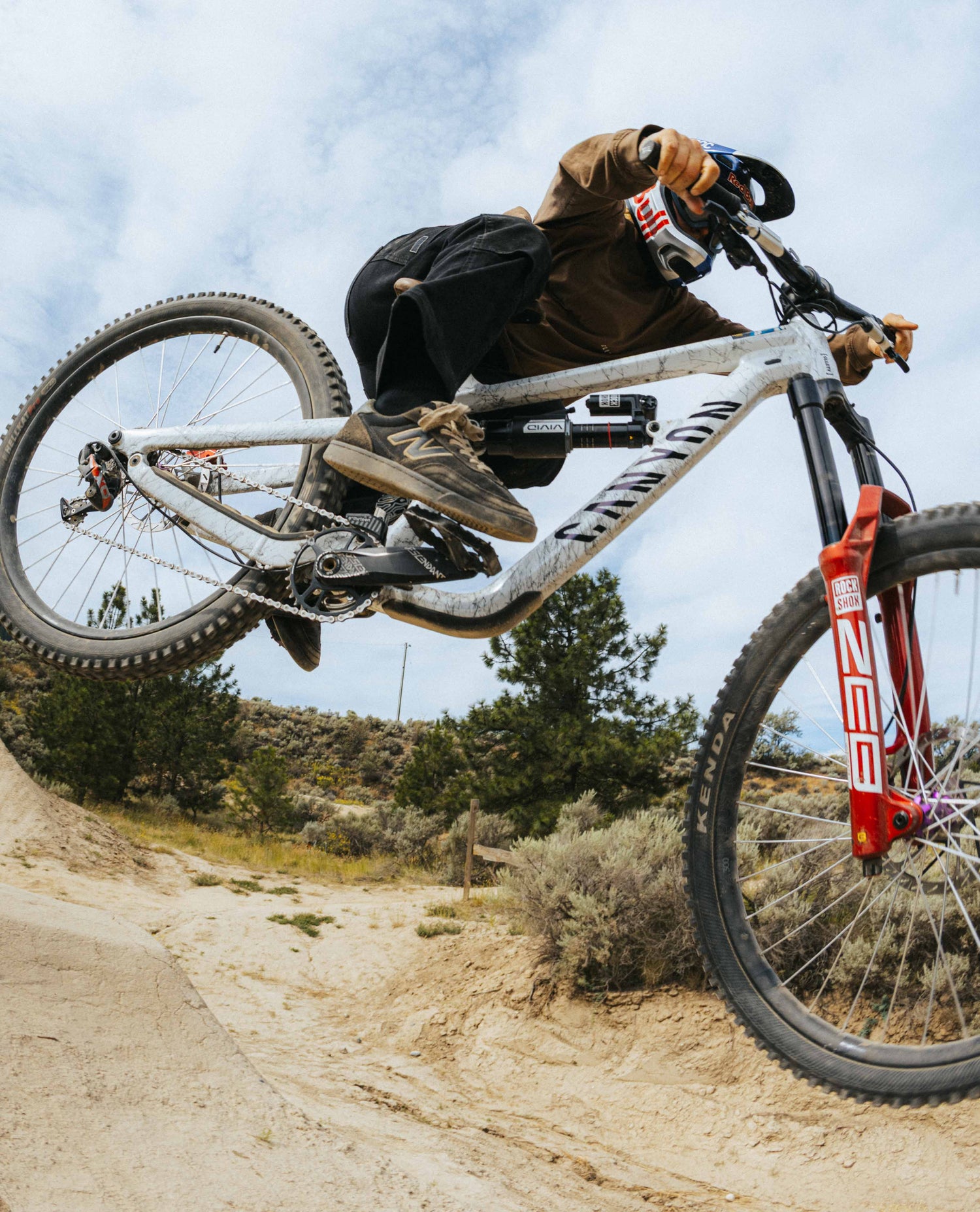 Person riding a mountain bike on a dirt trail with a clear sky.