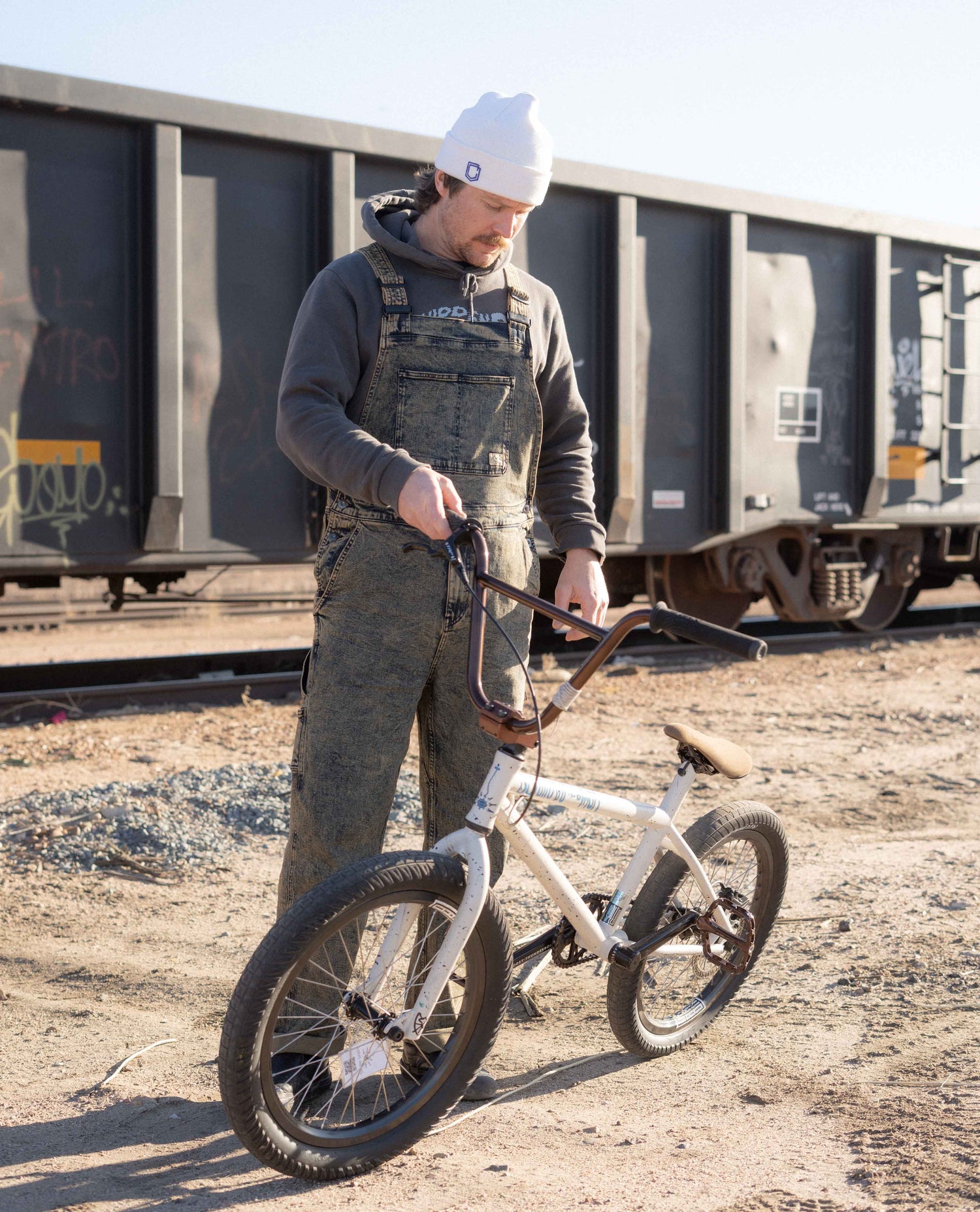 Myles in overalls by a train with a bike