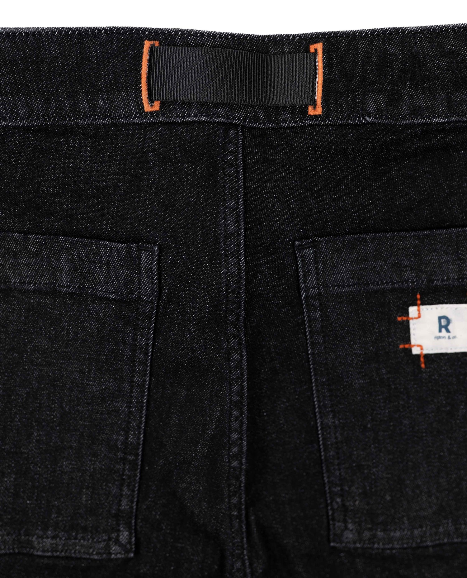 Close-up of black denim shorts with a brand label on the pocket.