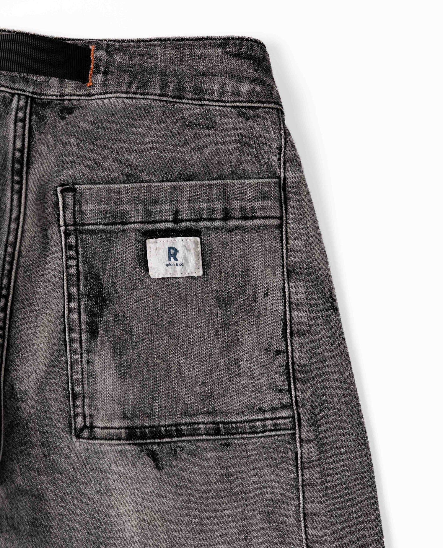 Close-up of a gray denim pocket with a brand logo on a white background