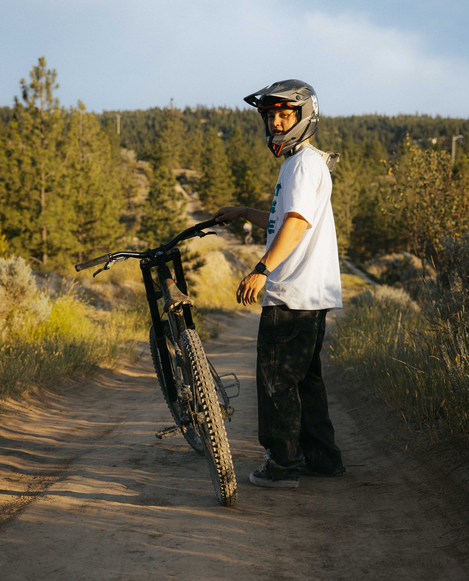 Person with a mountain bike on a dirt trail in a forested area