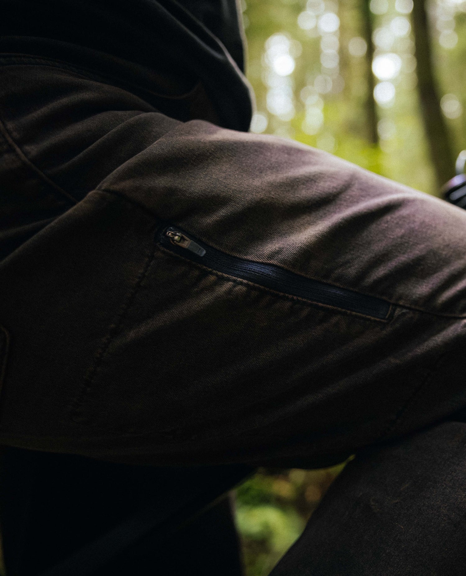 Close-up of a person wearing a dark jacket with a blurred forest background
