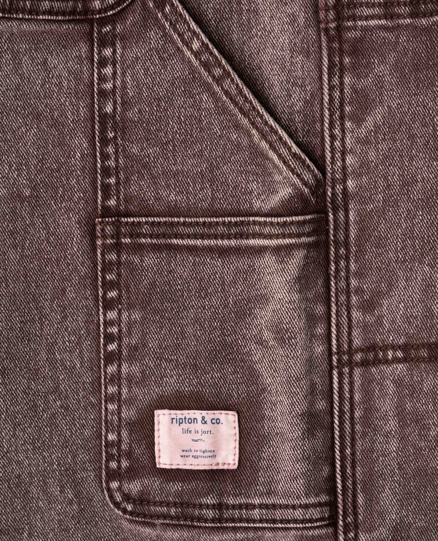 Close-up of a denim jacket with a brand label on a dark gray background