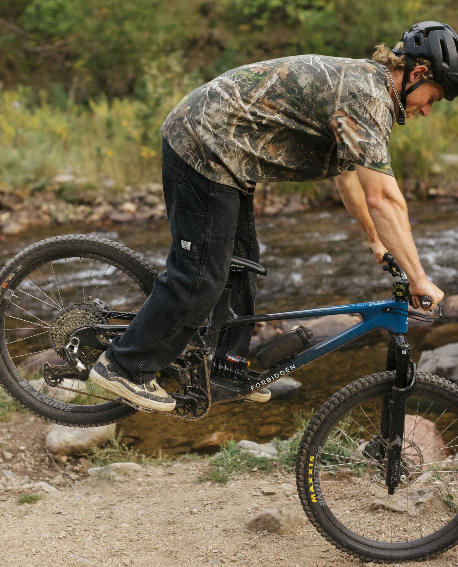 Person riding a mountain bike over a stream in a natural setting