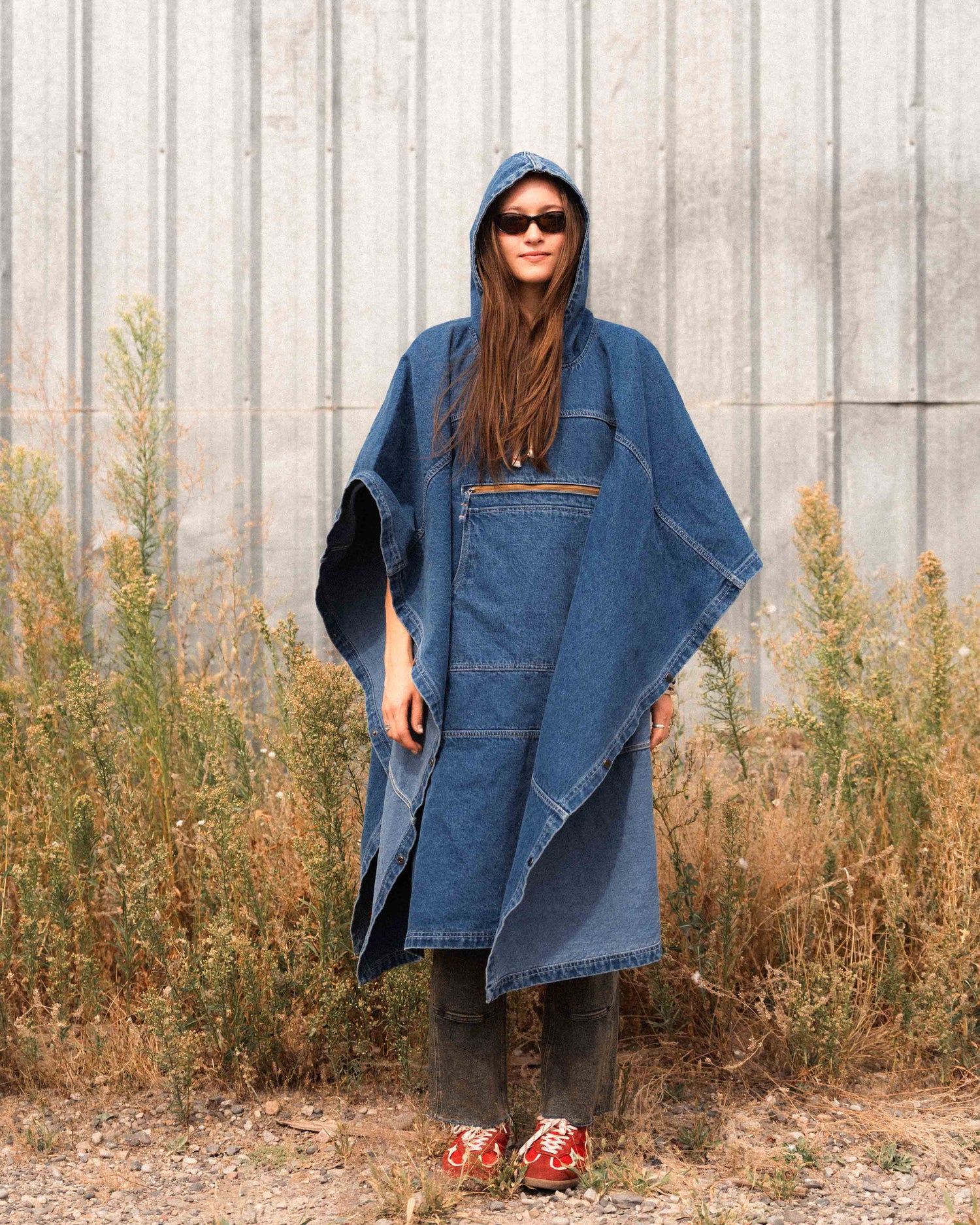 Person wearing a denim poncho in an outdoor setting