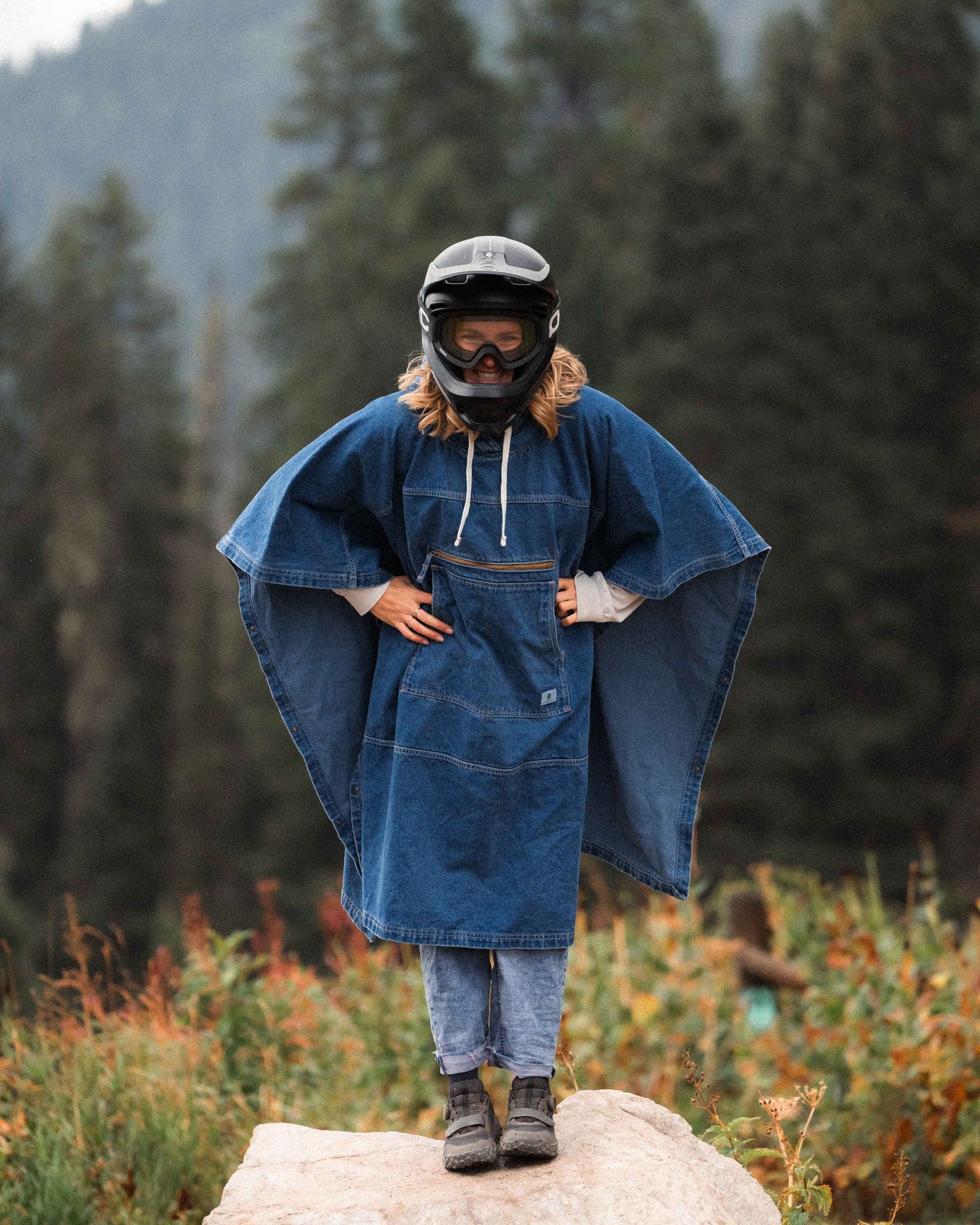 Person wearing a blue denim poncho in a forest setting