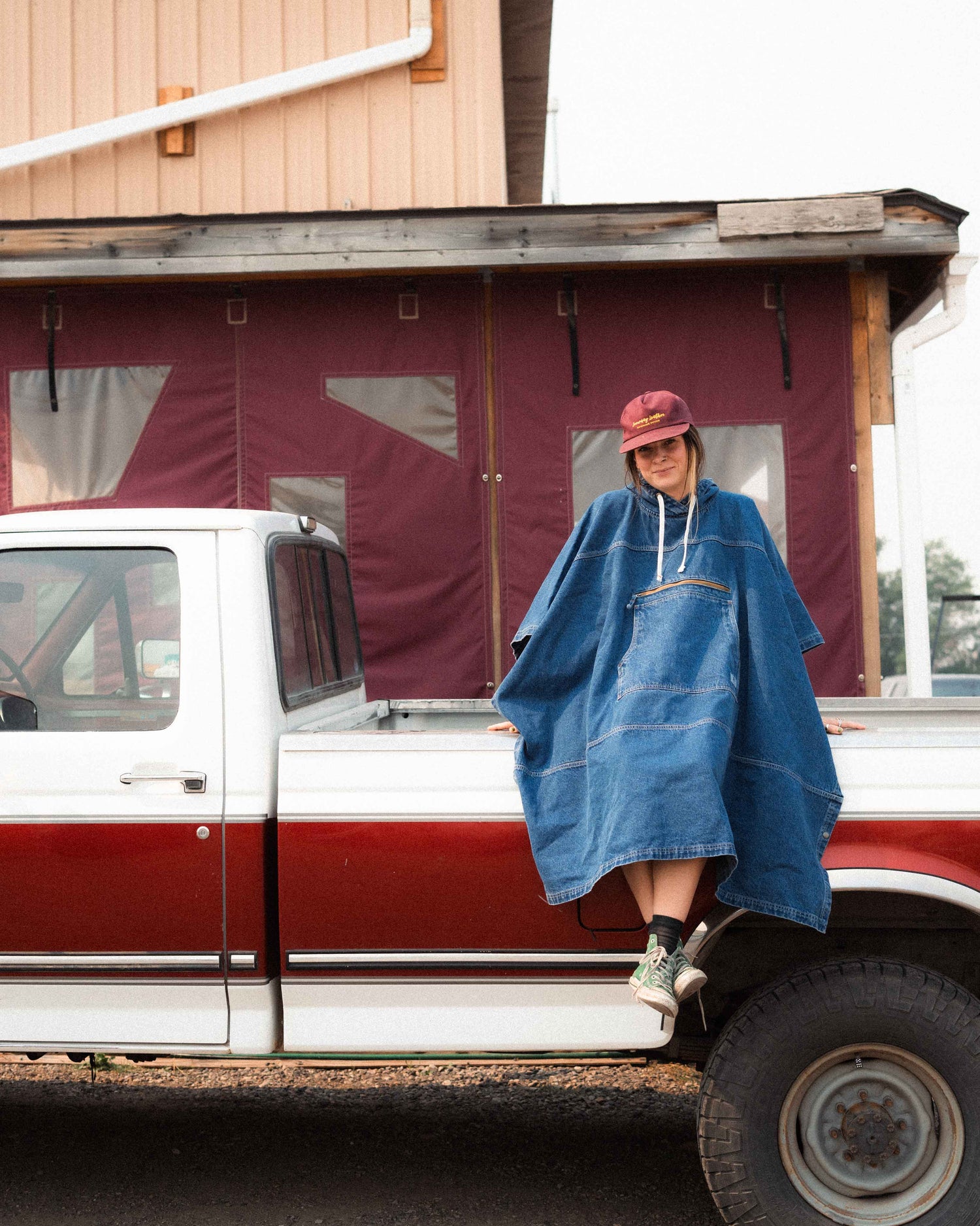 Person wearing a blue poncho sitting on a truck