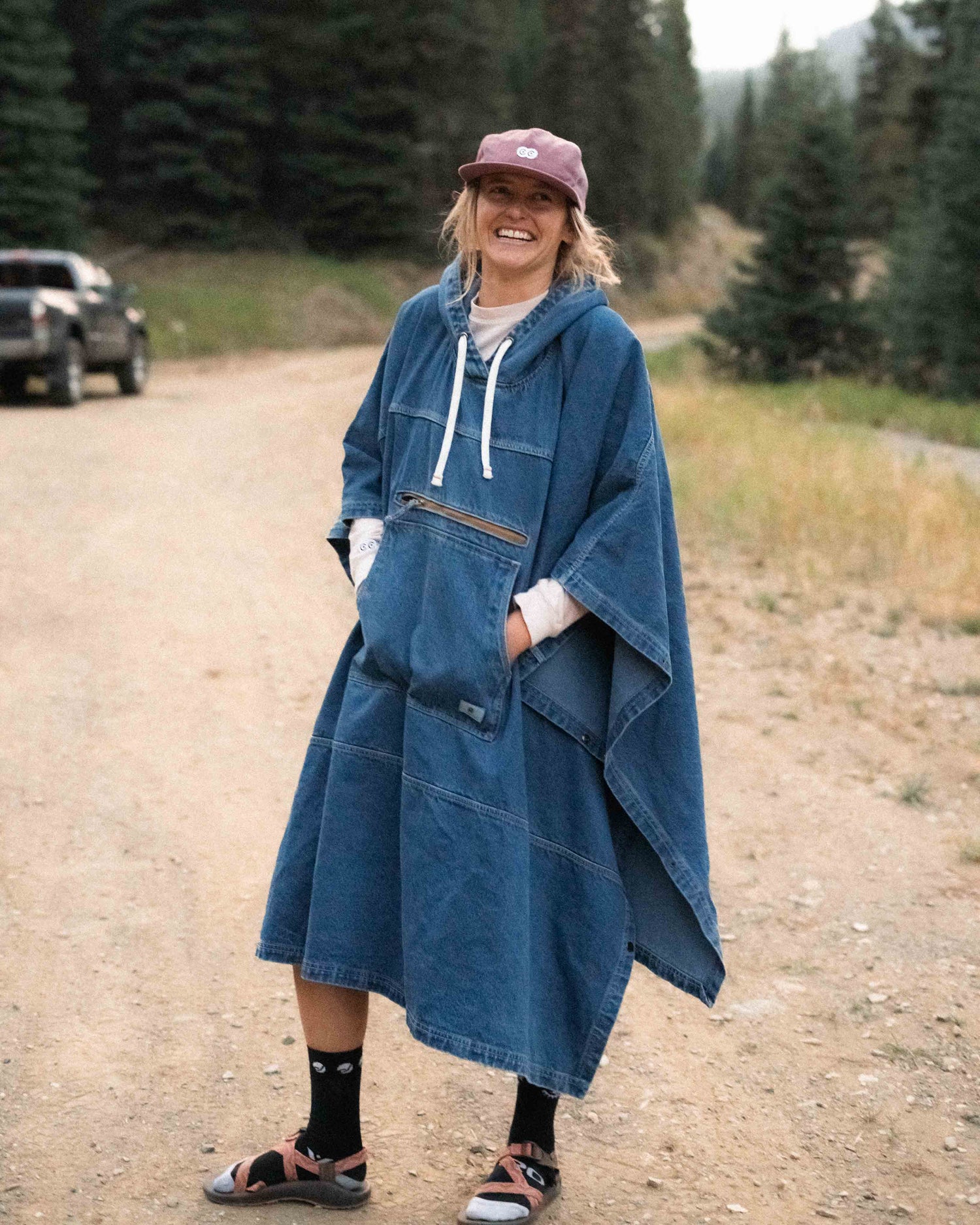 Person wearing a blue hooded poncho on a forest road.