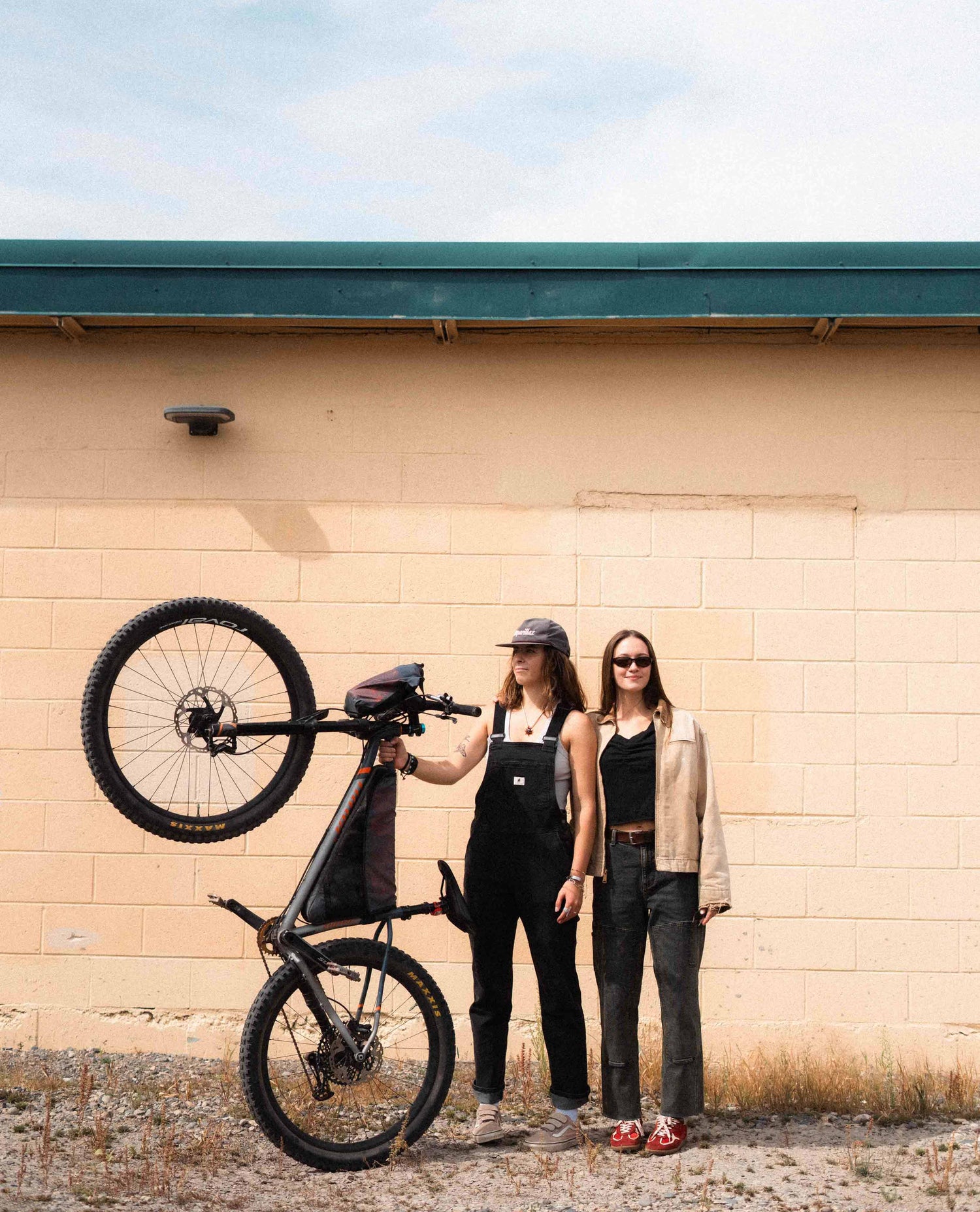 Two women standing against a wall.