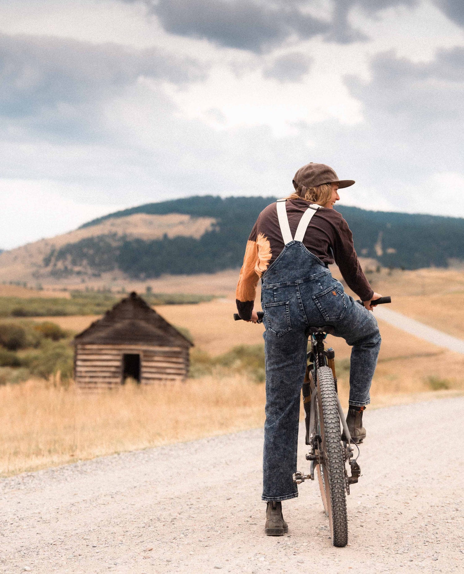 Woman sitting on a bike in Ripton Indigo Marble Overalls.