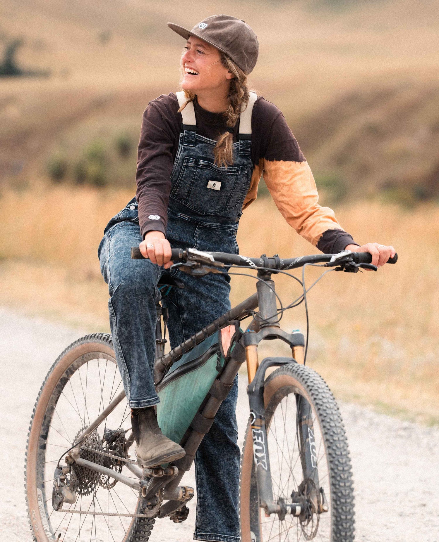 Woman sitting on a bike in Ripton Indigo Marble Overalls.
