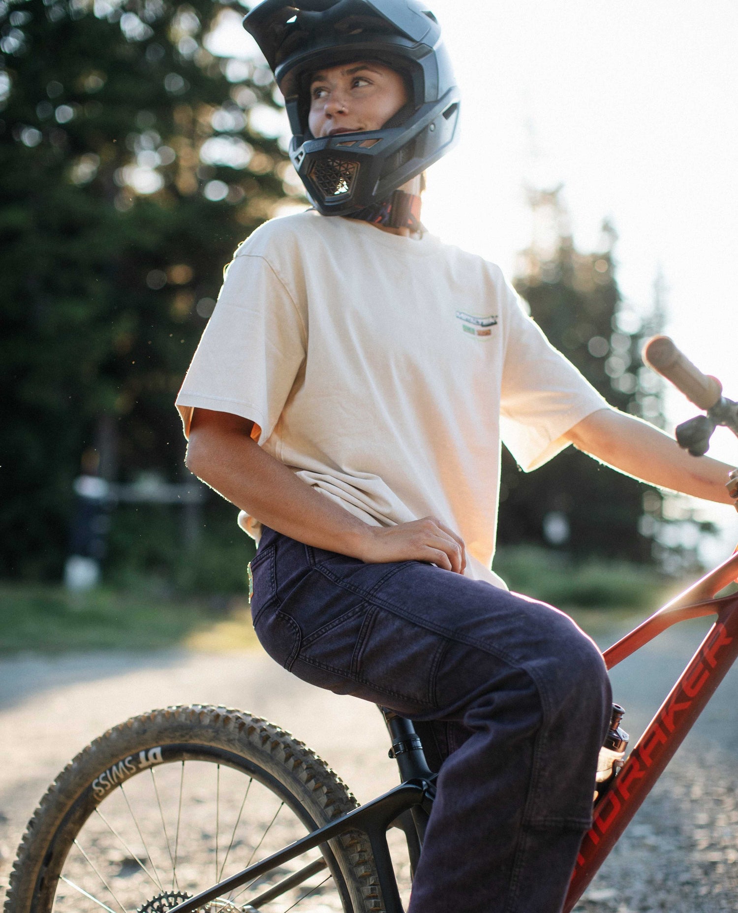 Person wearing a helmet and casual clothing, sitting on a bicycle outdoors.