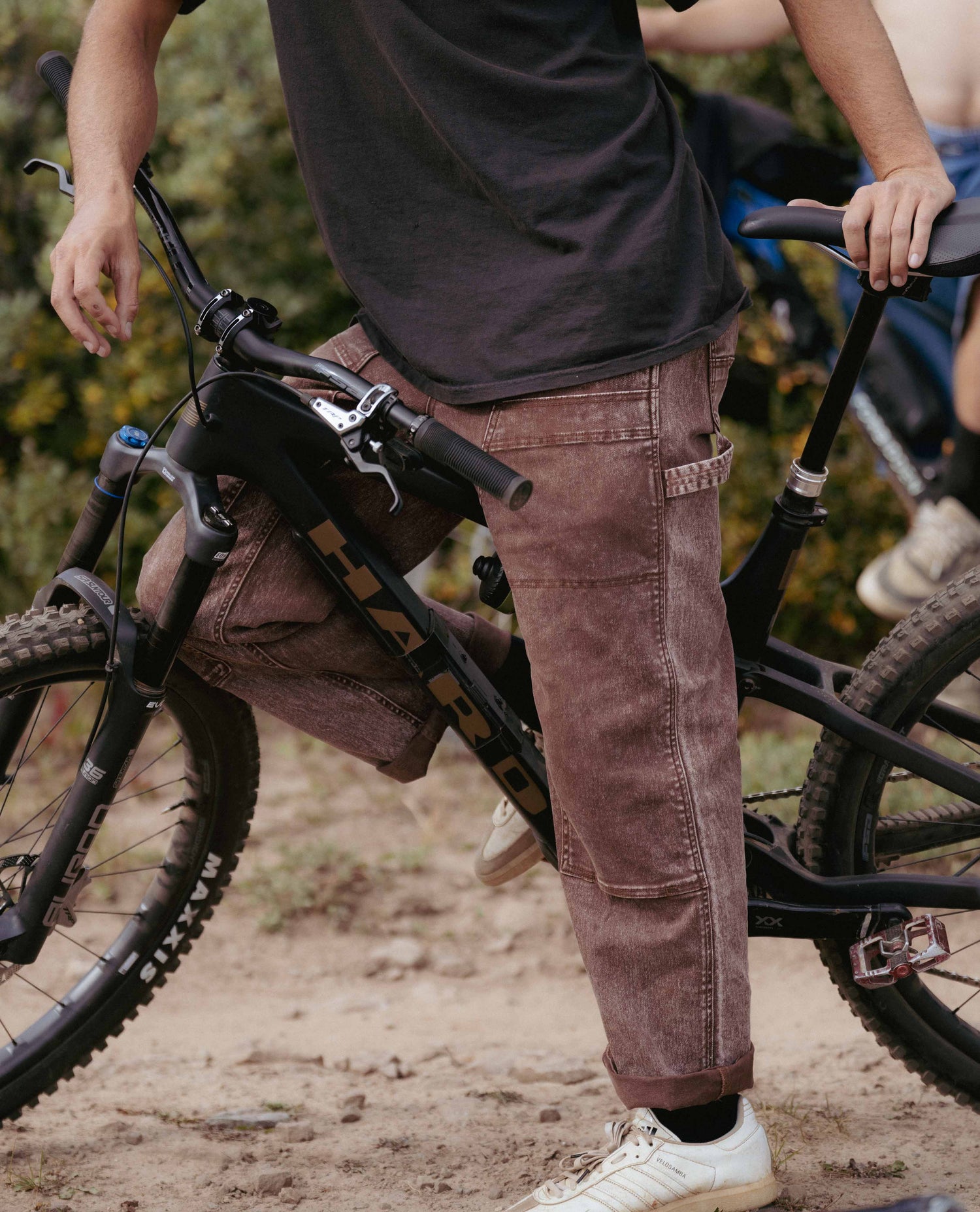 Person wearing brown cargo pants and white sneakers on a bike path