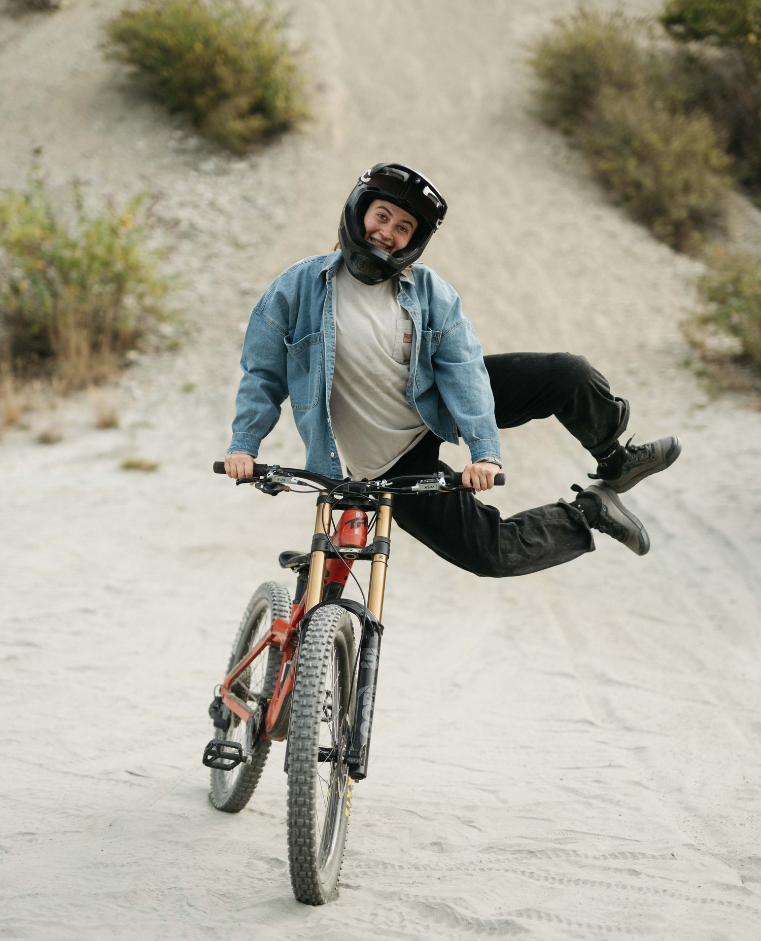 Person riding a mountain bike on a dirt path with a helmet on