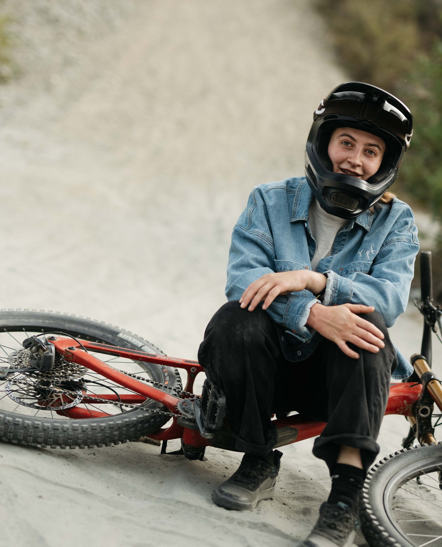 Person sitting on a bicycle wearing a helmet and casual clothing, with a blurred natural background.