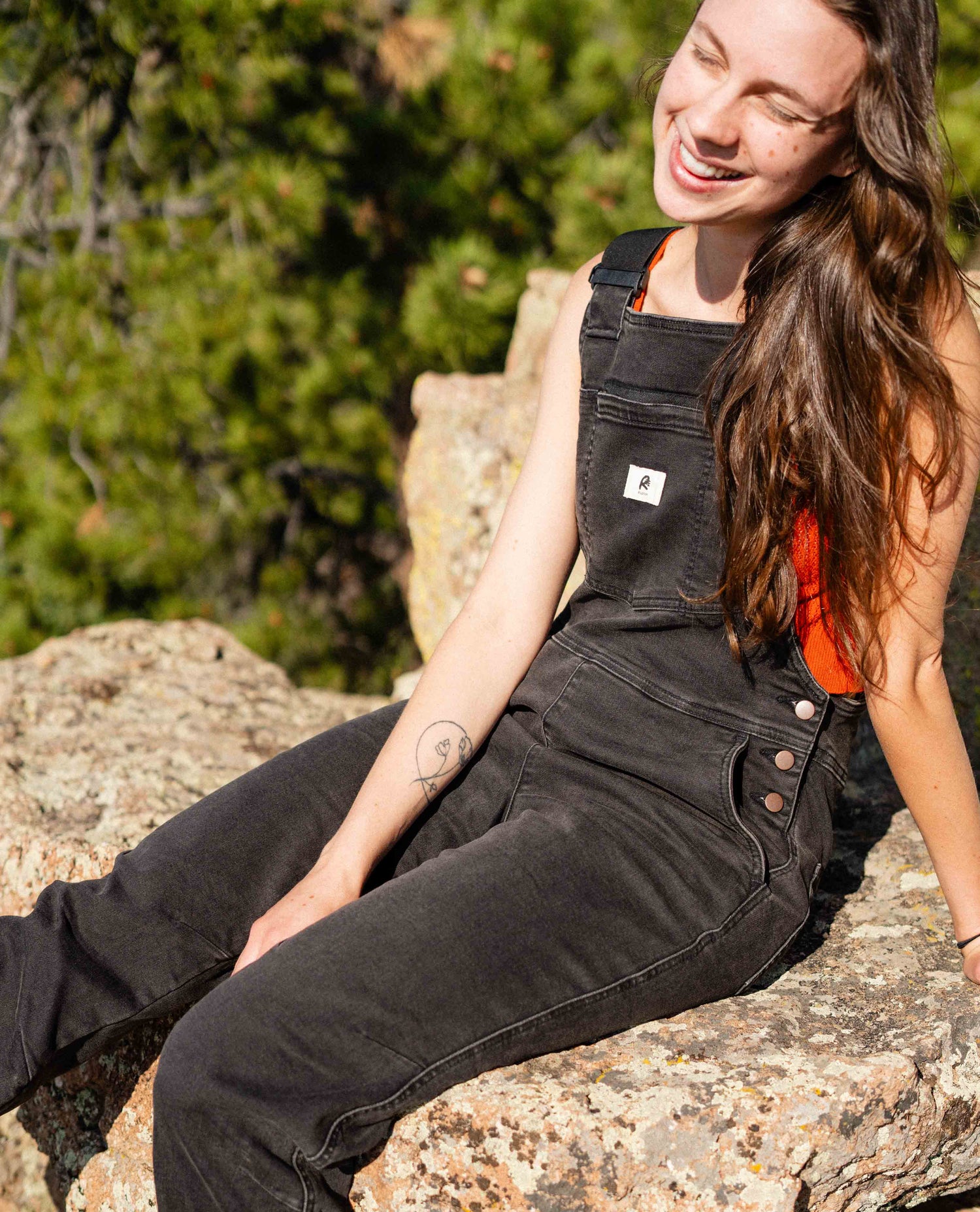 Girl sitting on rock in Ripton overalls.