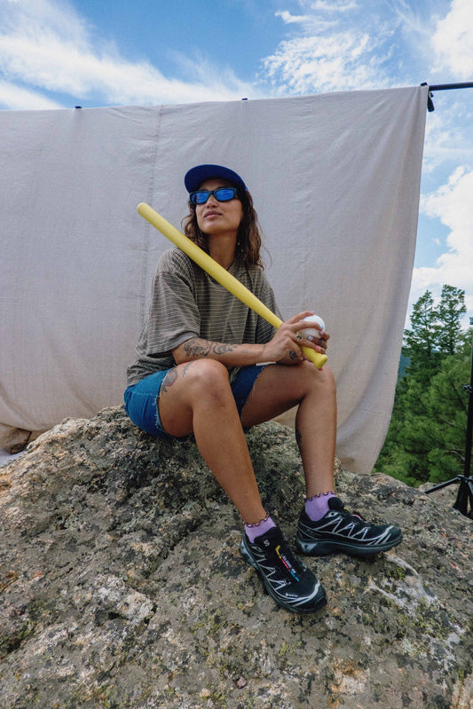 Woman with baseball bat outside.