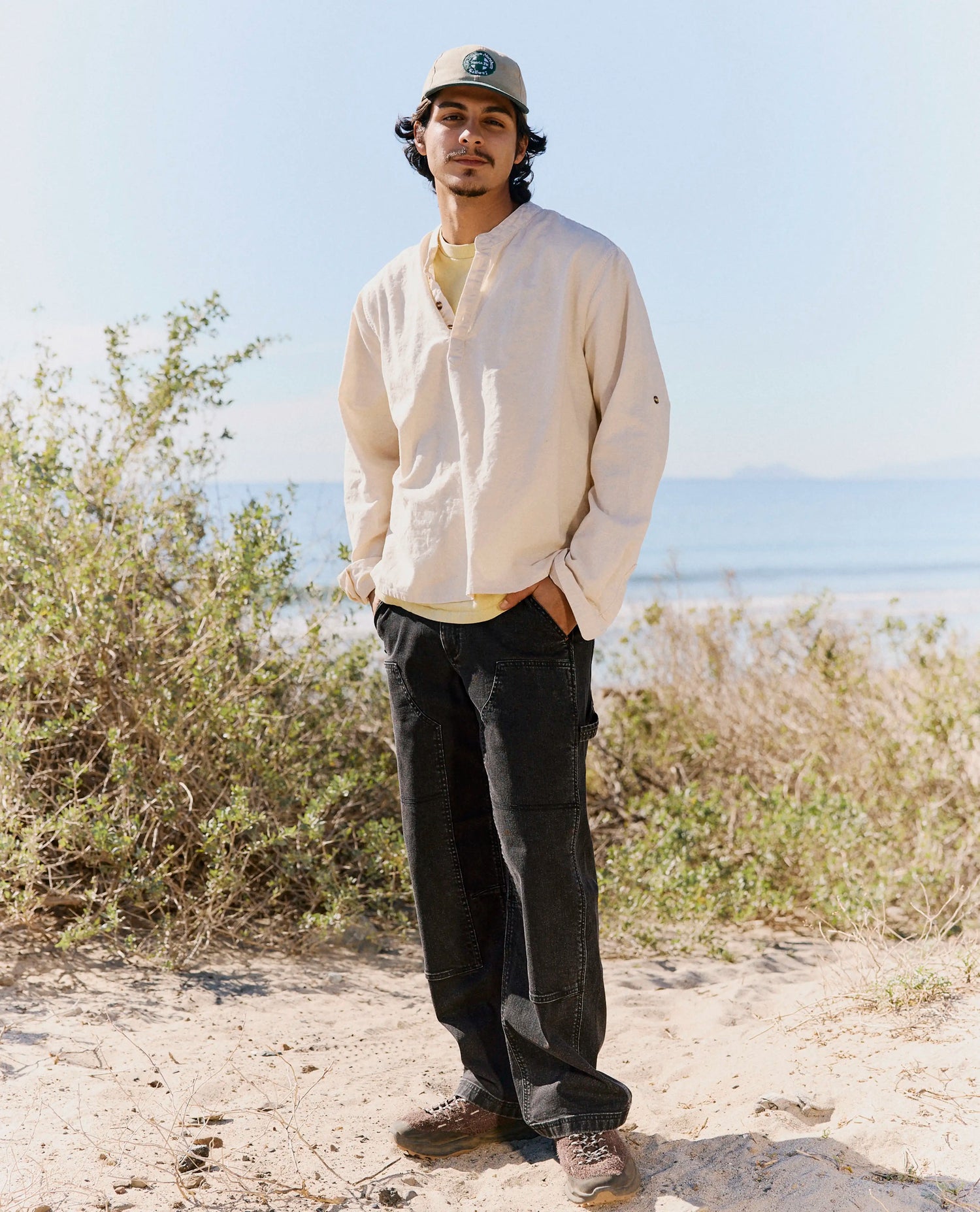 Person standing outdoors with a scenic background of trees and water.