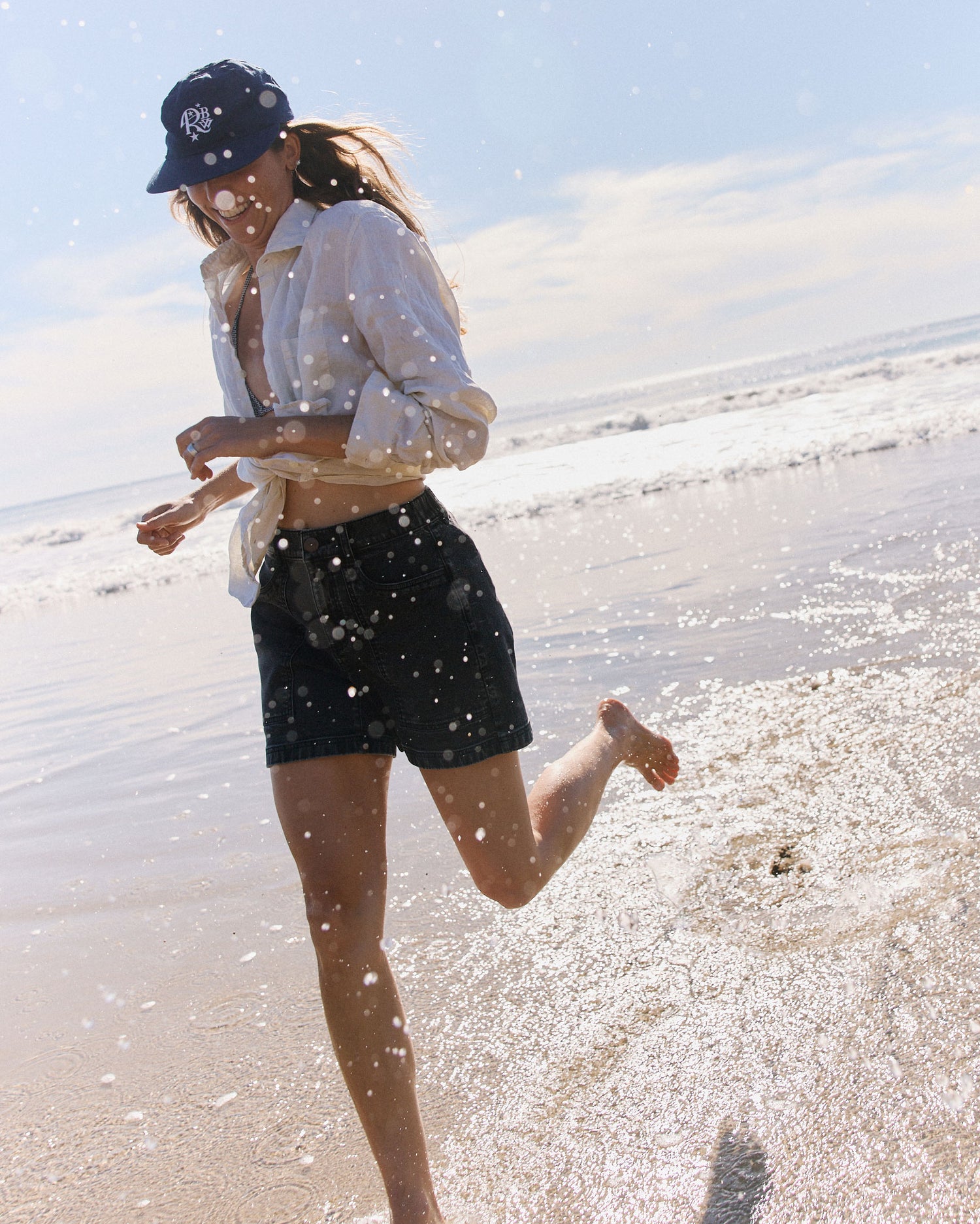 Person running on a beach with water splashing around