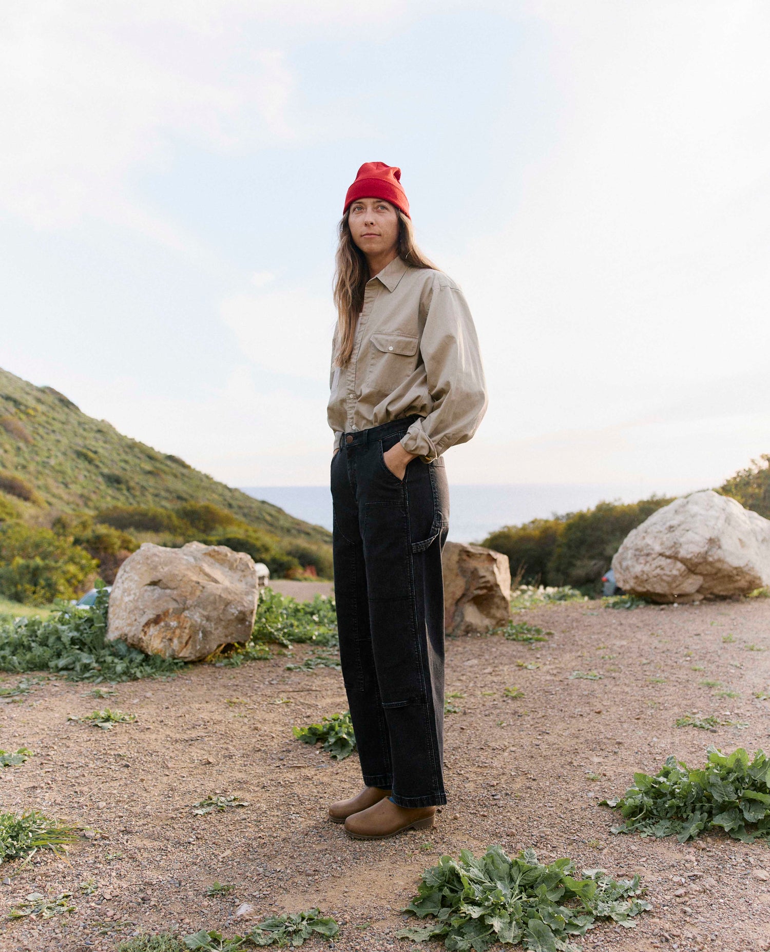 Person standing outdoors in a natural setting with mountains and rocks.