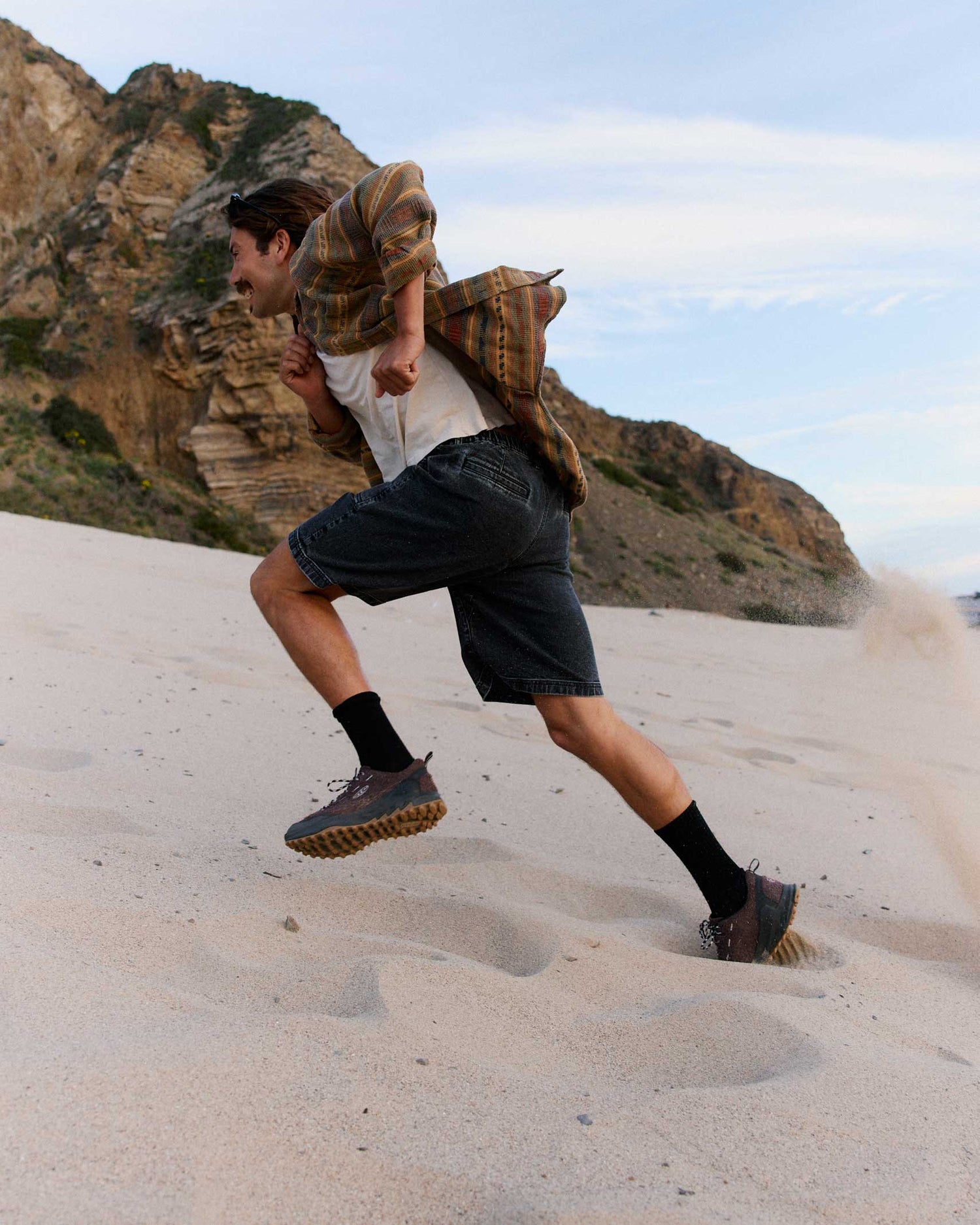 Person running on sand with mountains in the background