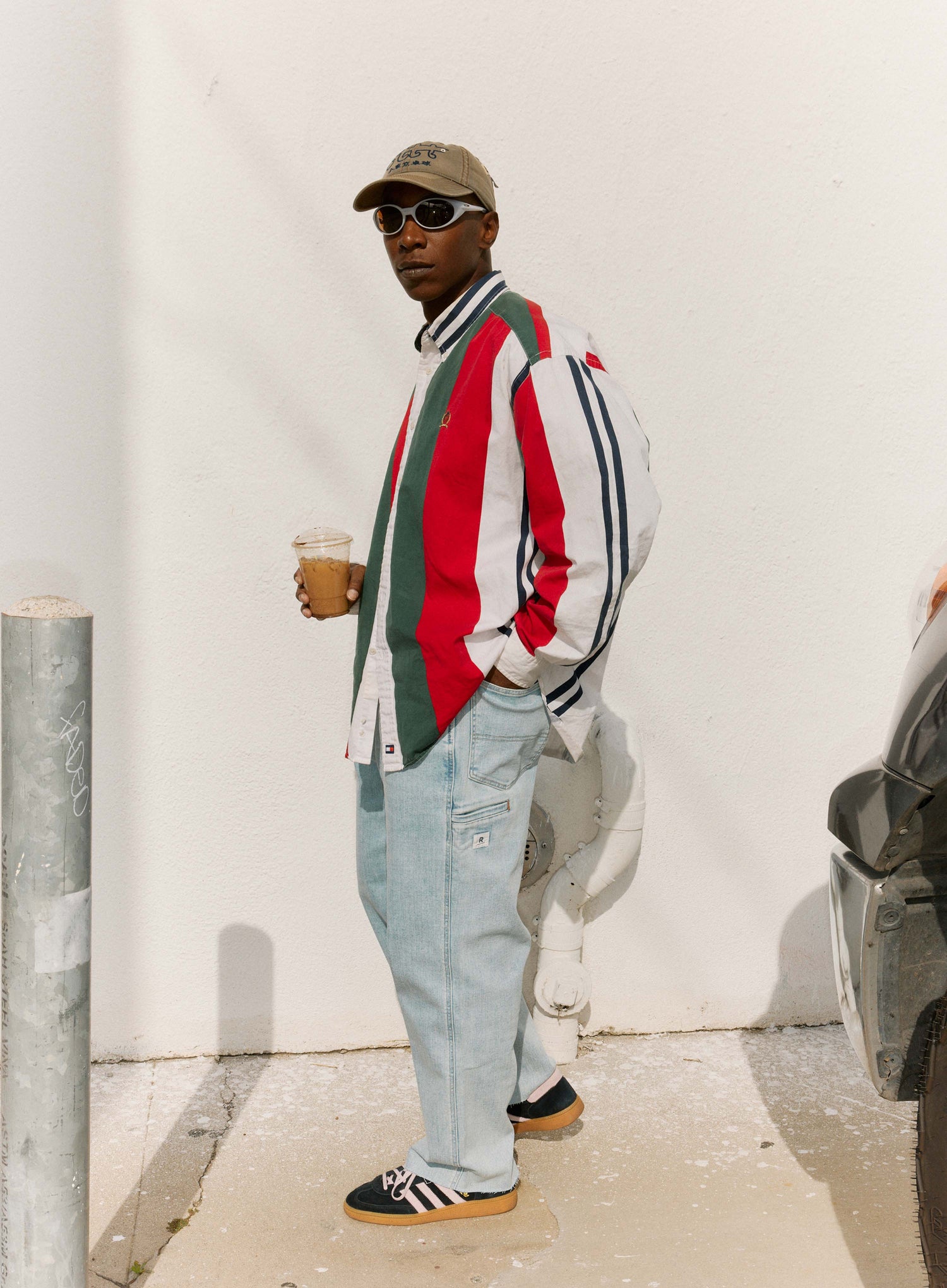 Person wearing a colorful striped sweater and light jeans, standing against a white wall.