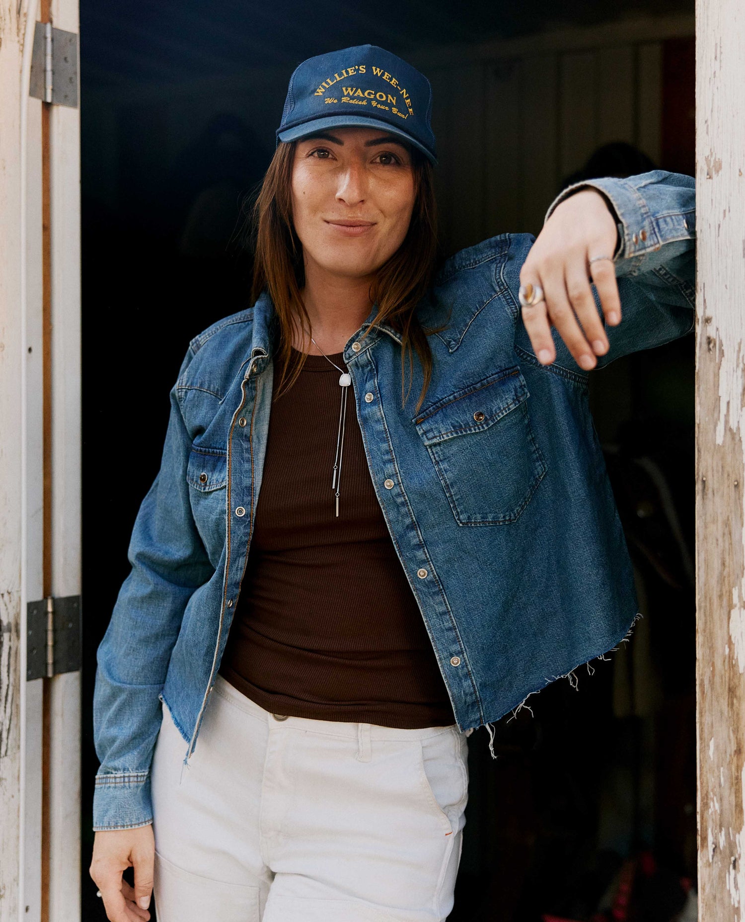 Girl wearing a blue denim shirt with a blue hat and white pants