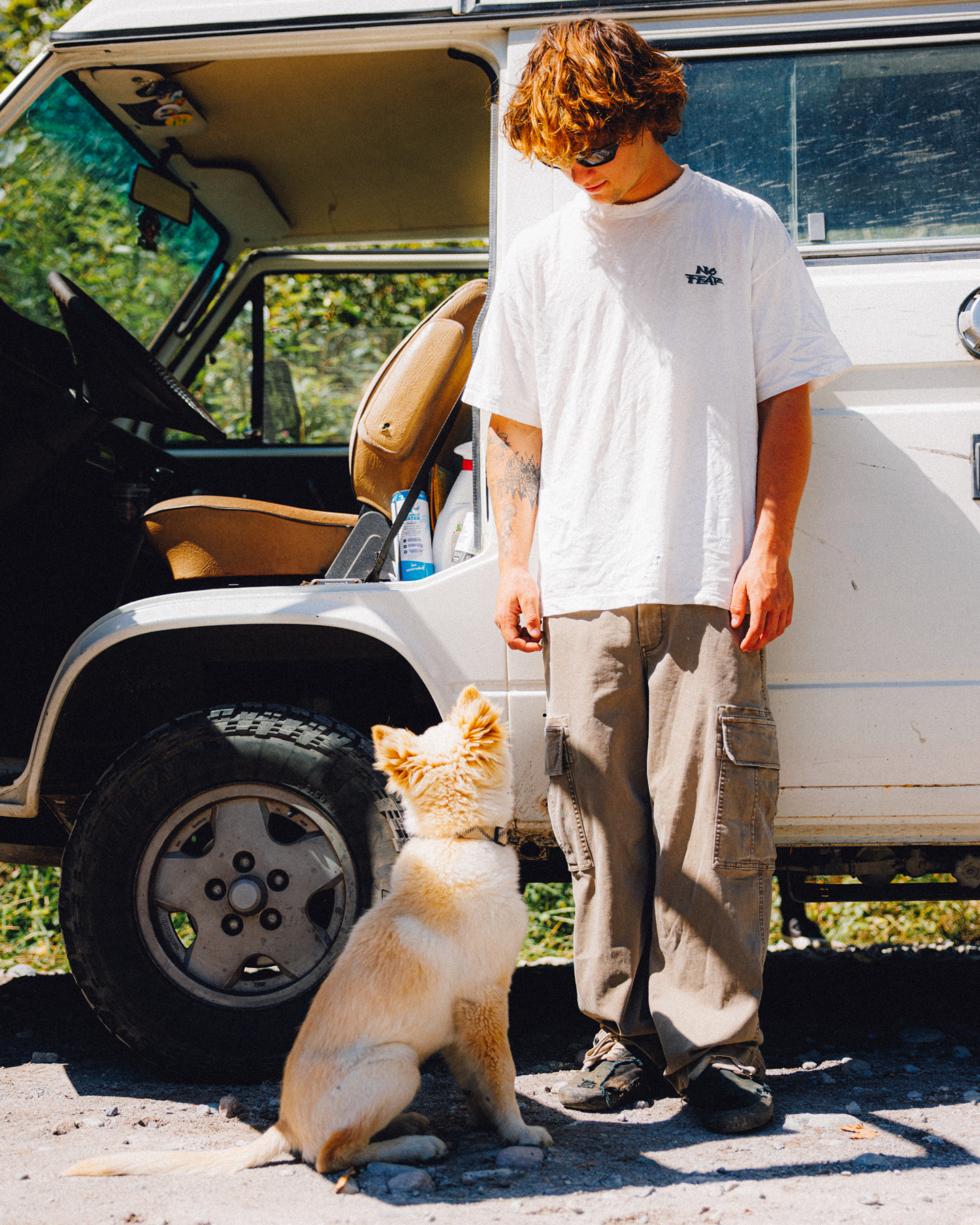 Man wearing brown cargo pants beside a dog and white camper van