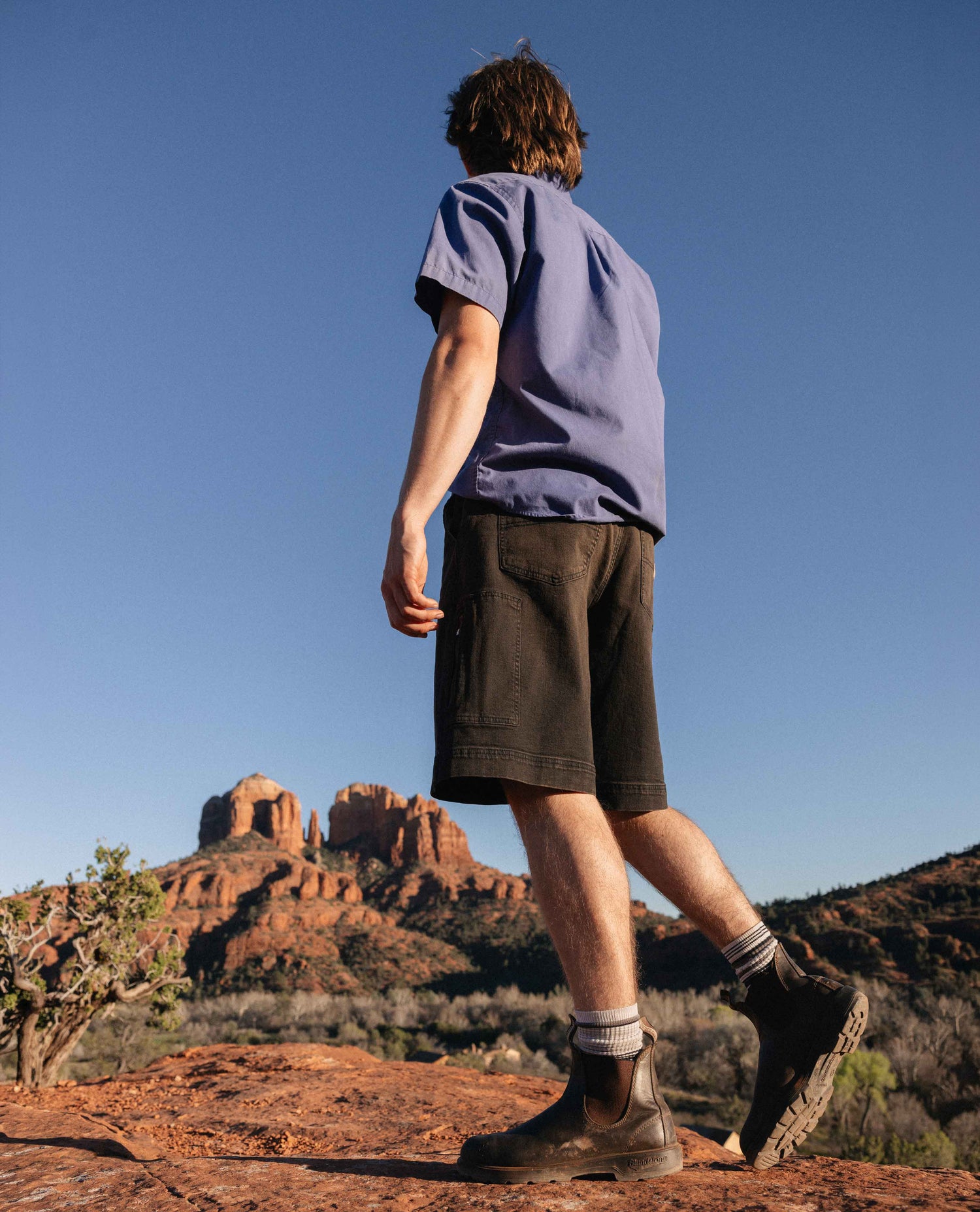 Person standing on a rocky outcrop with a scenic desert landscape in the background