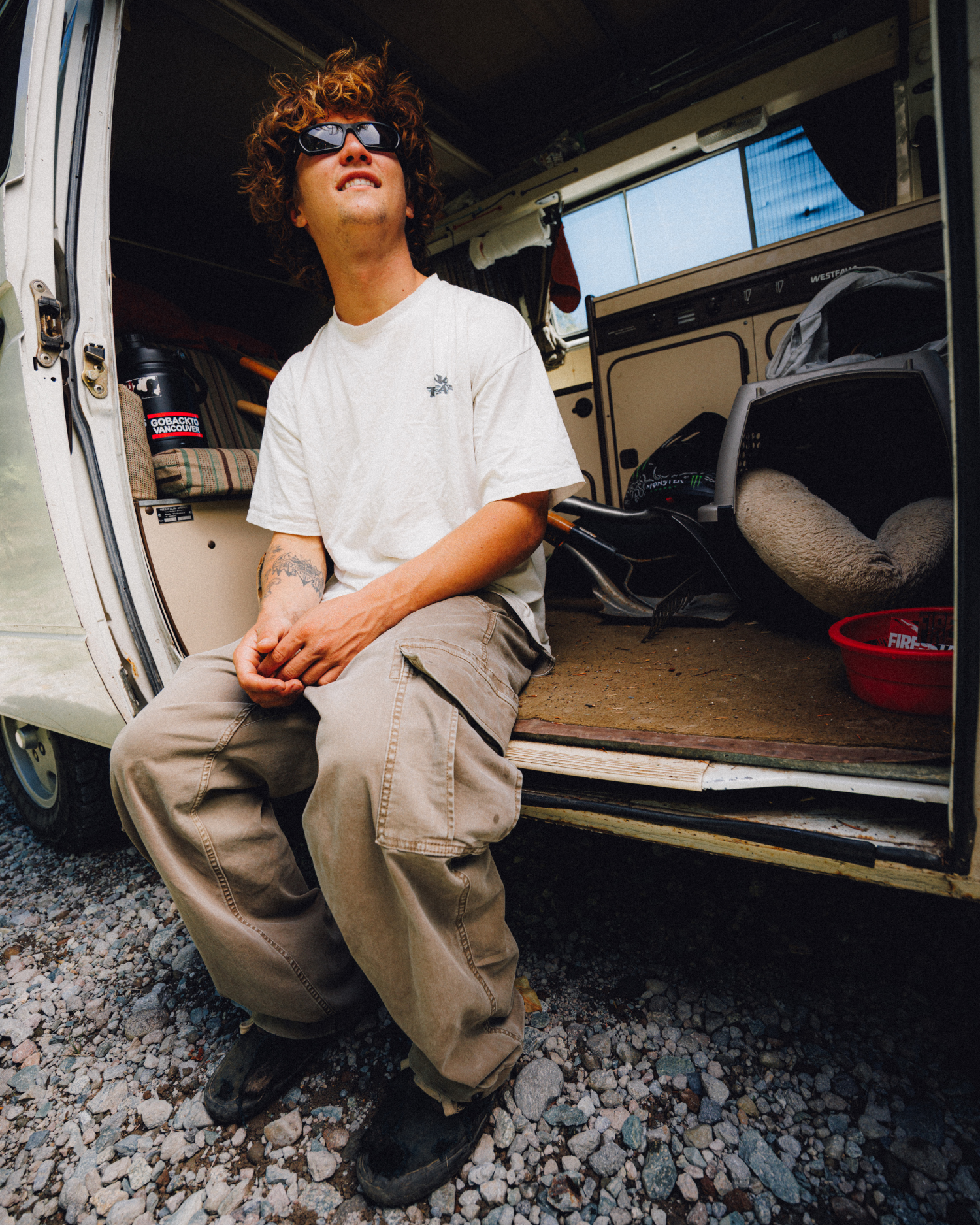 Man wearing loose brown cargo pants while sitting in the doorway of a camper van