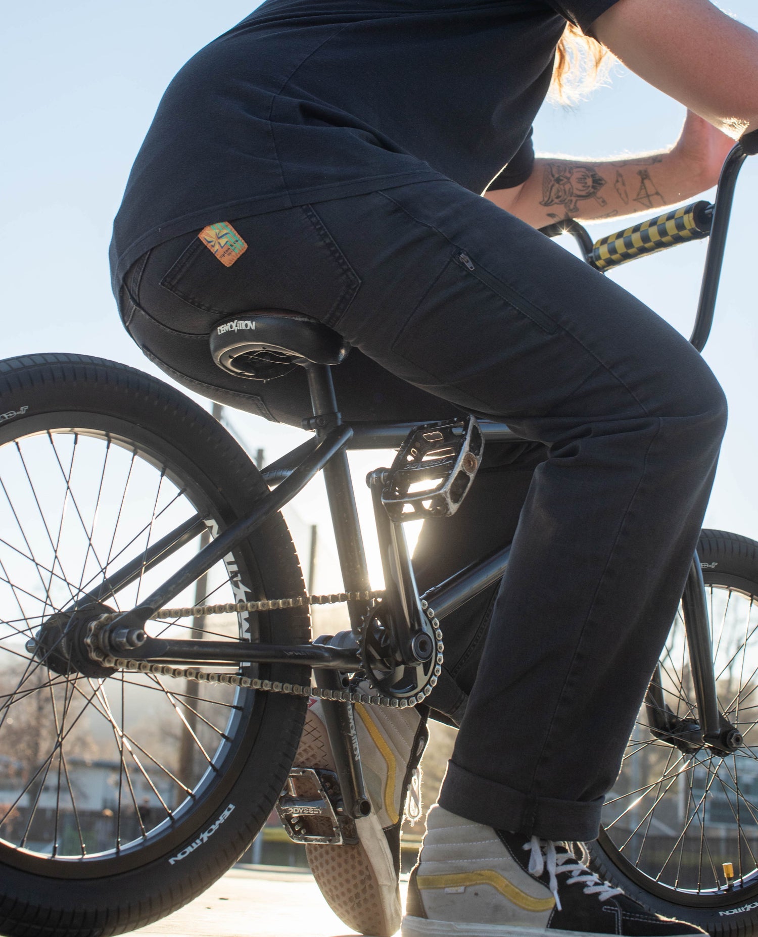 A man sitting on a bmx bike wearing a pair of black jeans and a black shirt. 