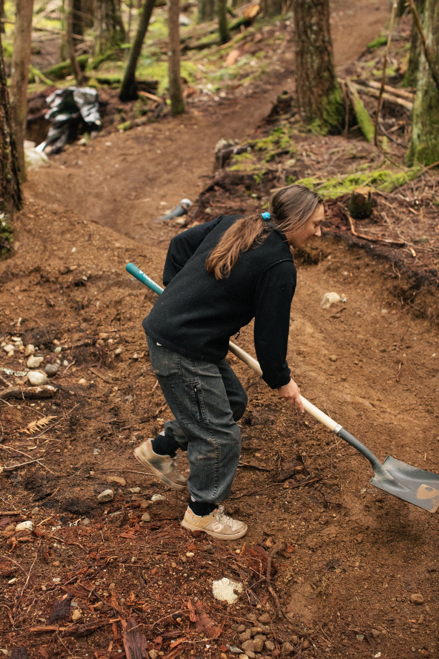 britt using a shovel on a forest trail