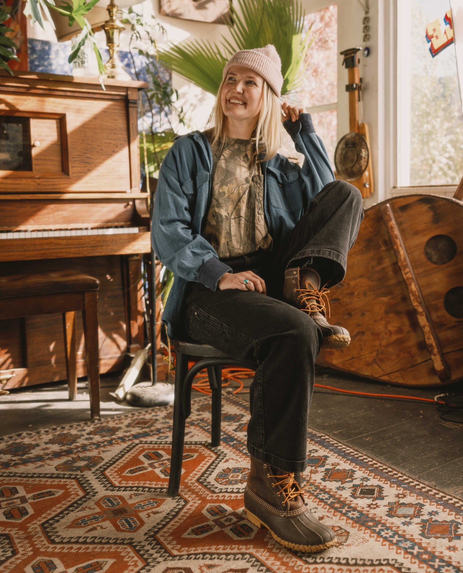 Person sitting on a chair in a room with a piano and decorative rug