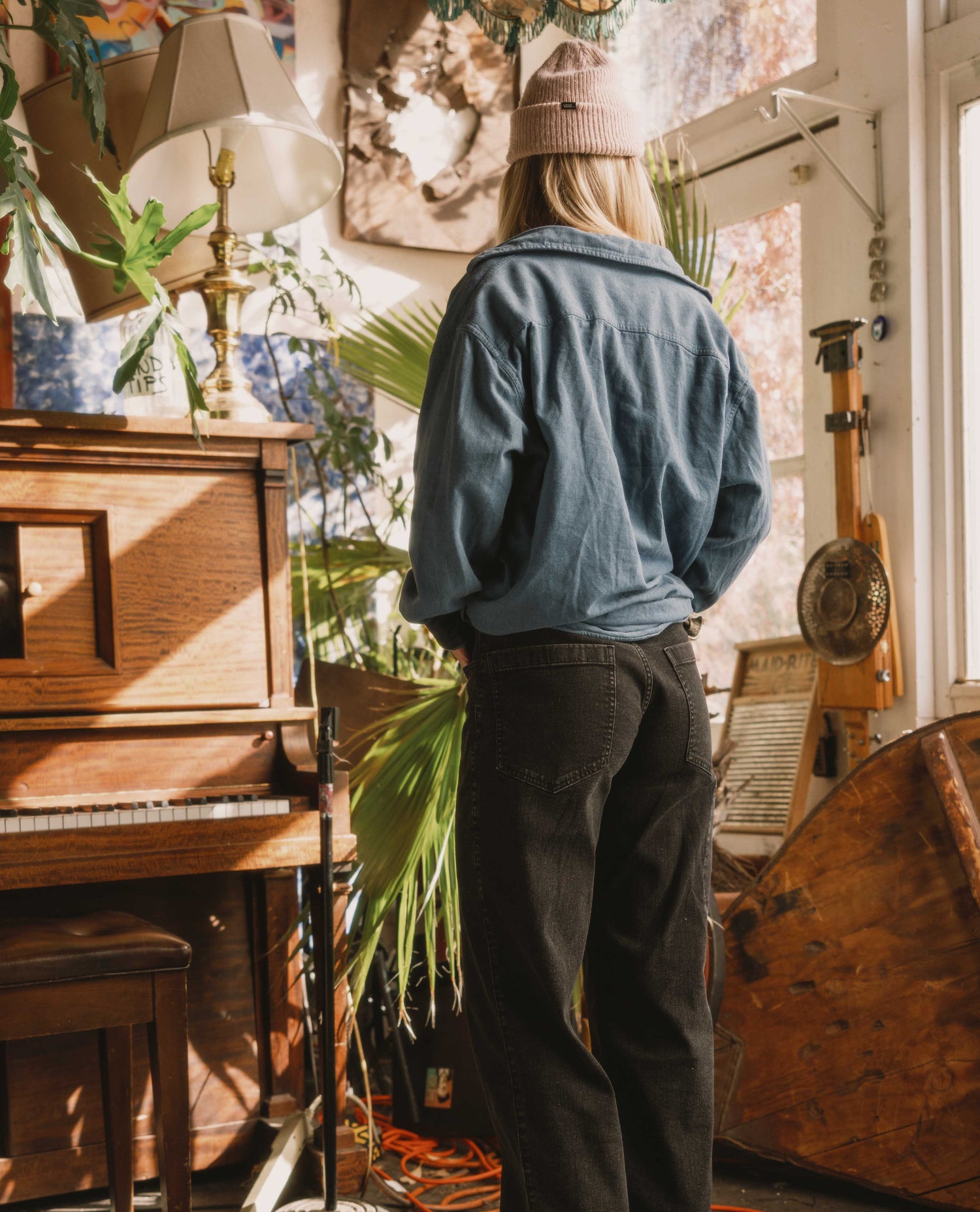 Person standing in a room with plants and musical instruments