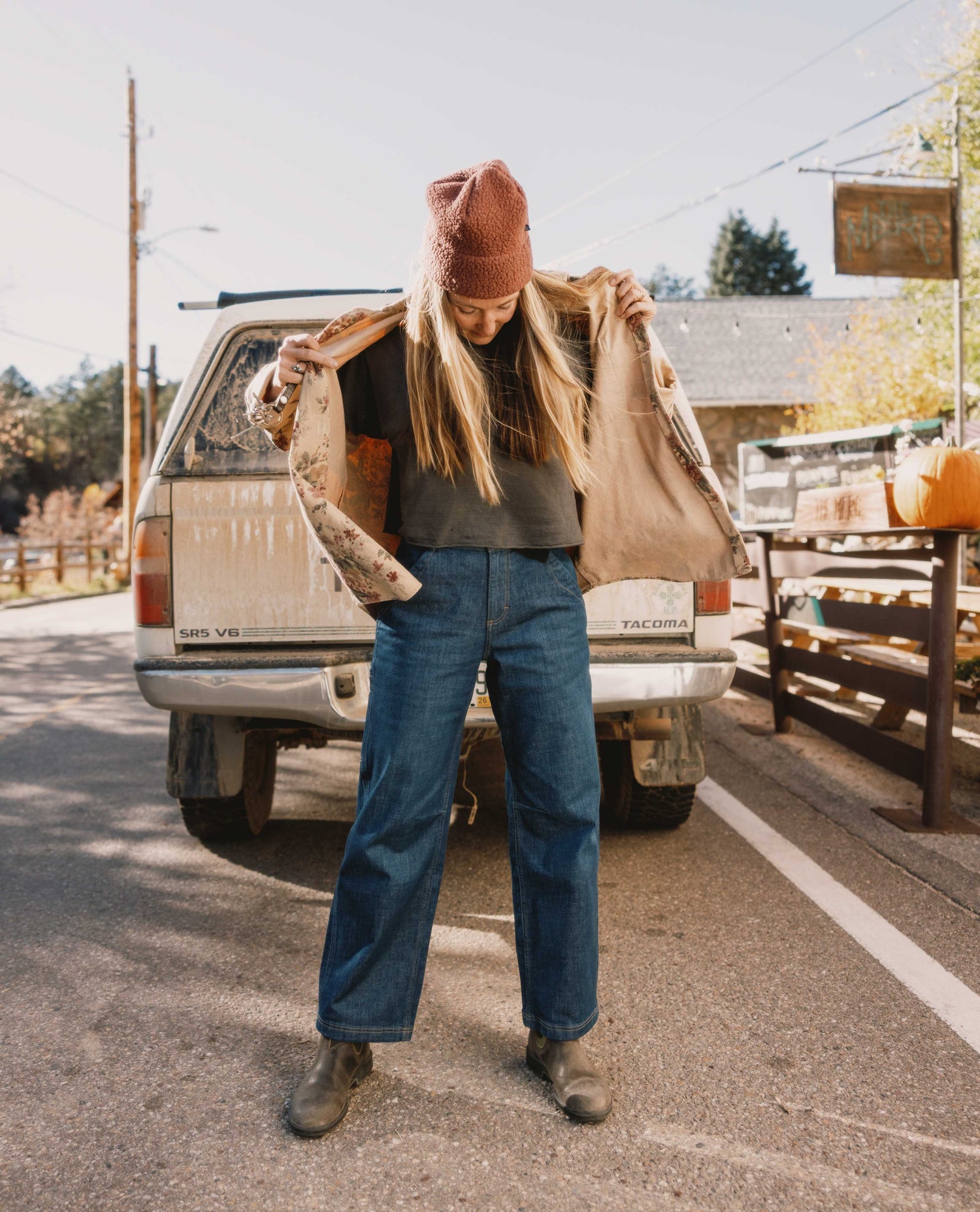 Person holding a jacket in front of a truck with a scenic background