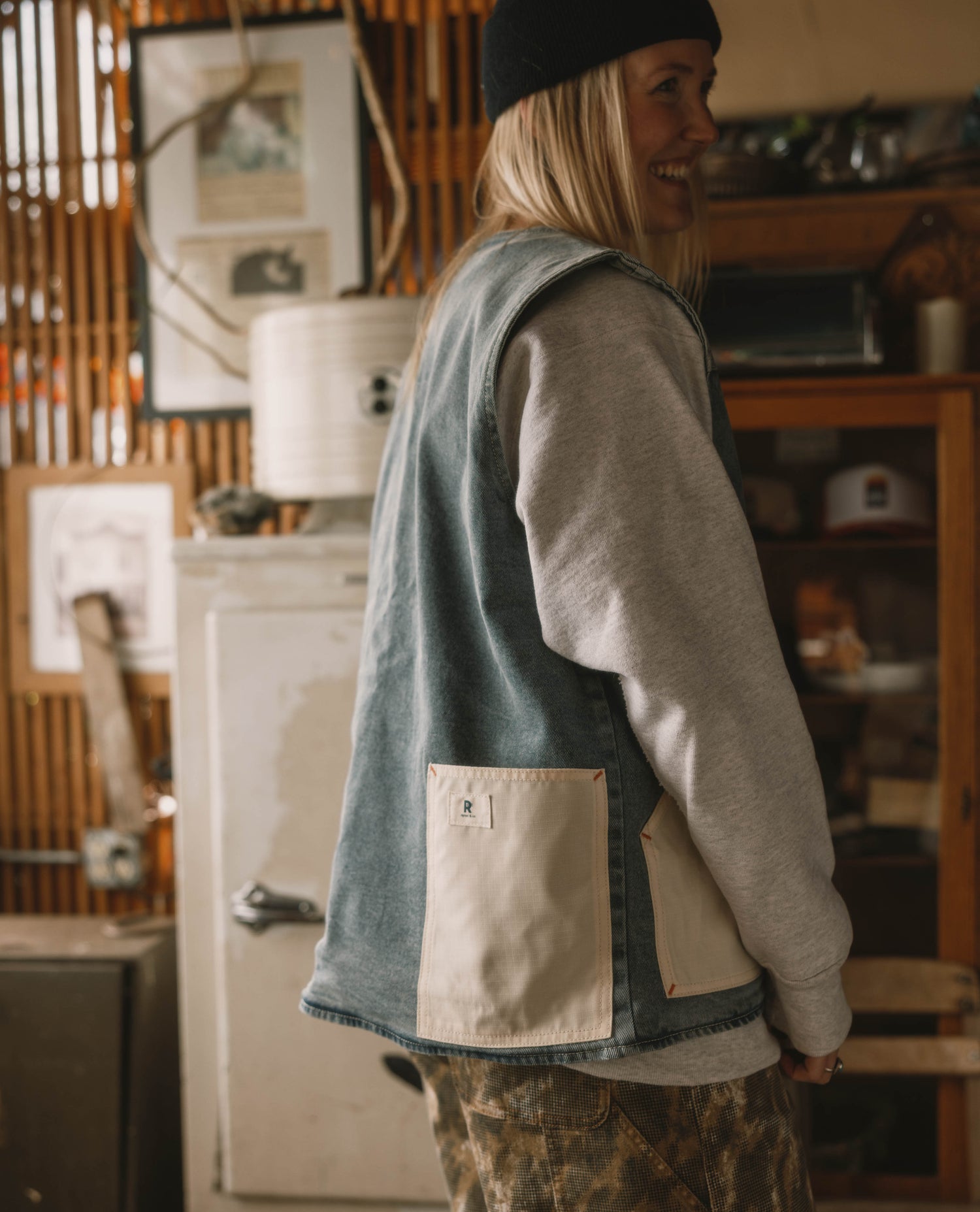 Person wearing a green vest with a beige pocket in a rustic indoor setting