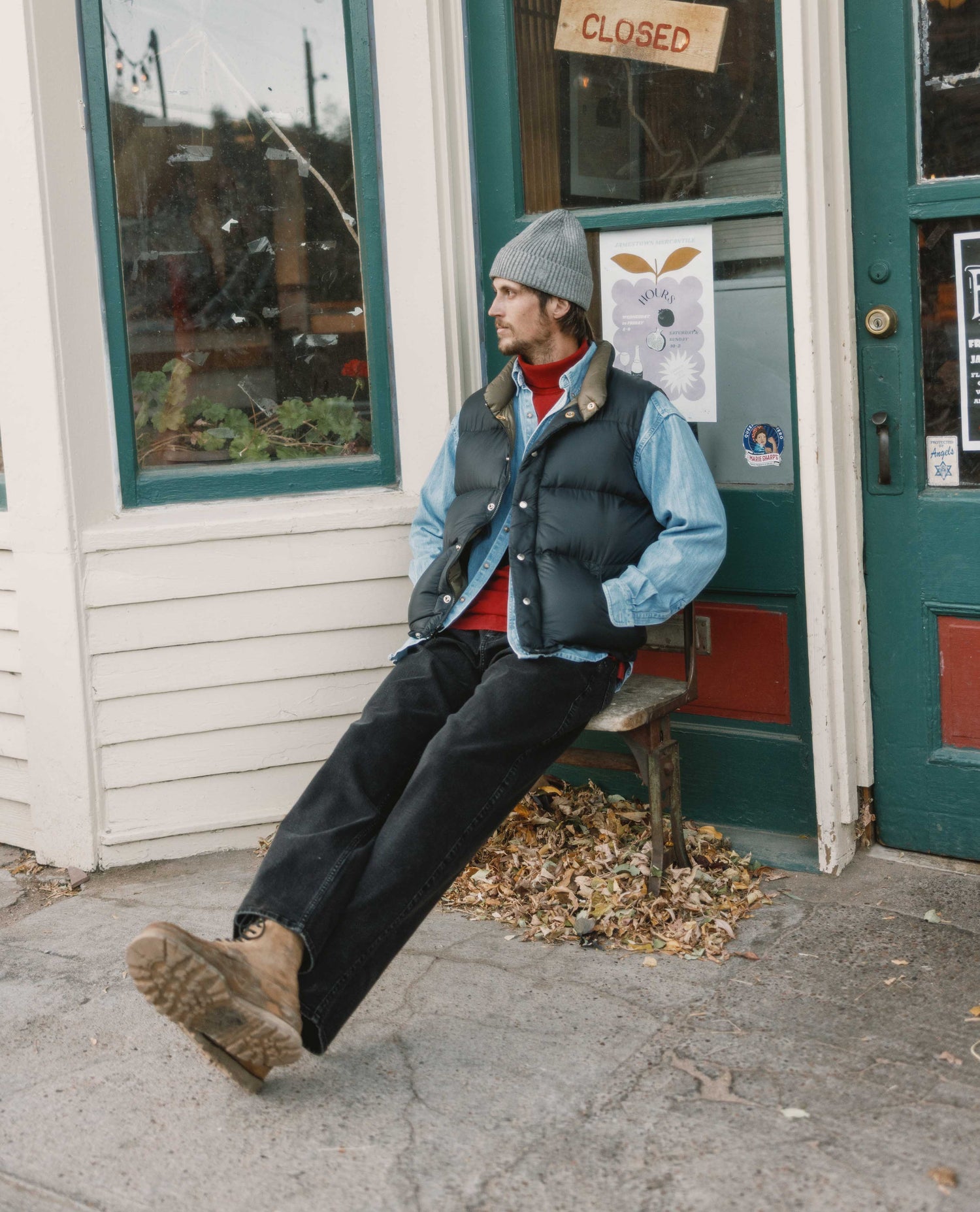 Person sitting on a chair outside a building with a 'Closed' sign.