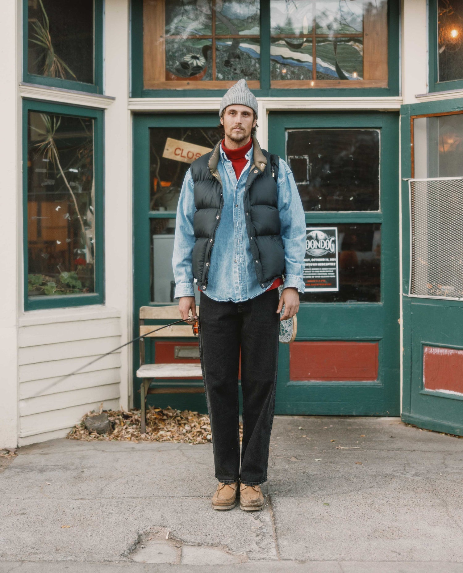 Man standing outside a building with green doors and windows.