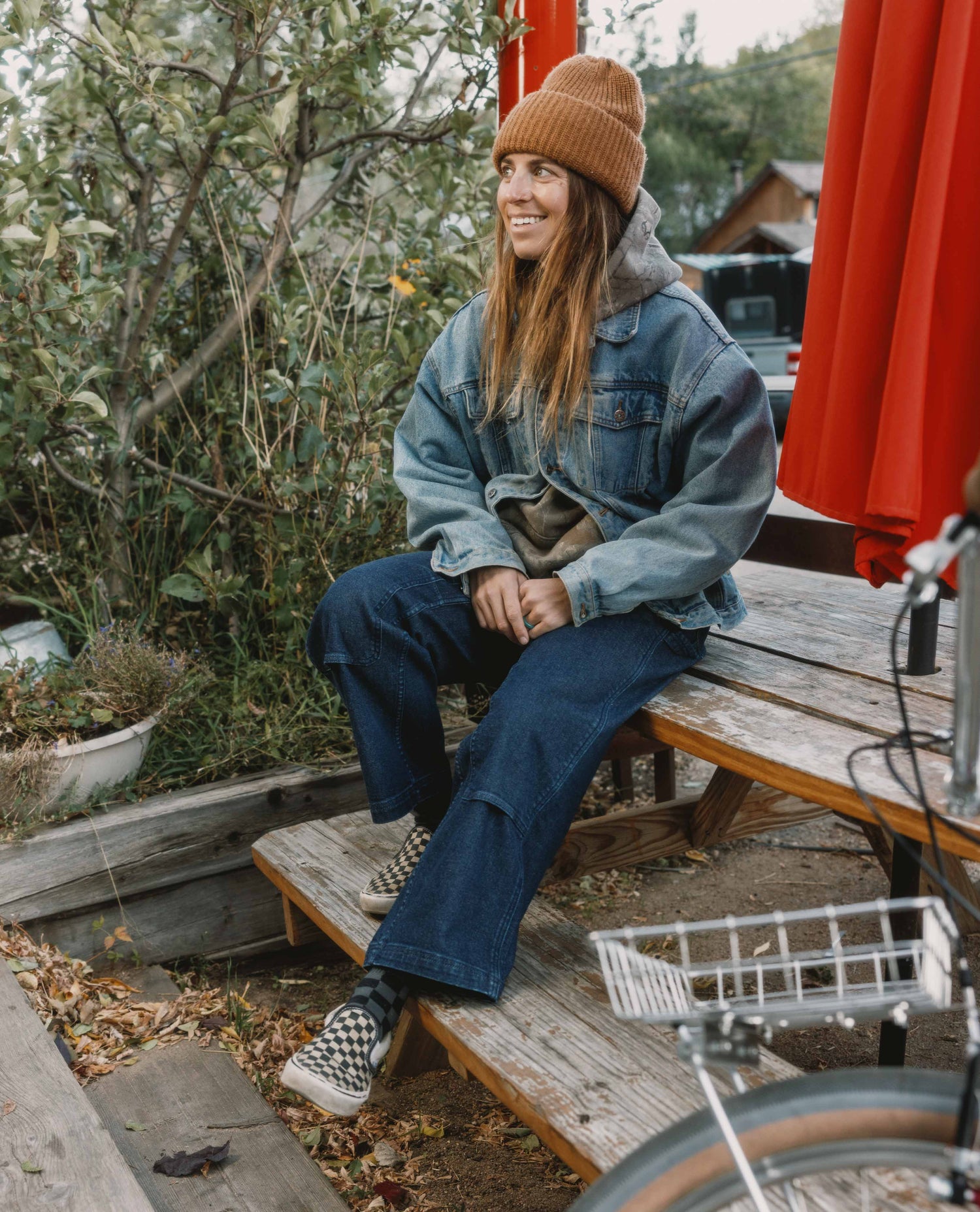Person sitting on a wooden bench outdoors with a bicycle in the foreground