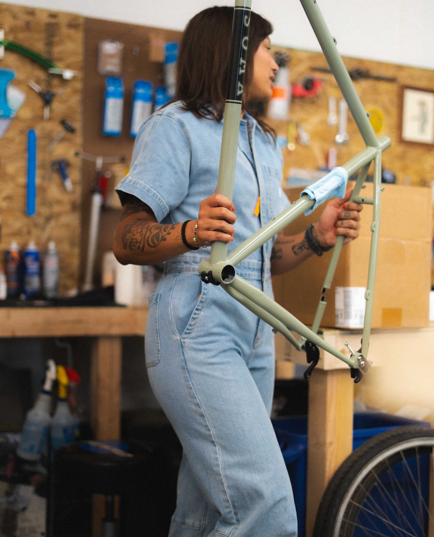 Person holding a bicycle frame in a workshop setting