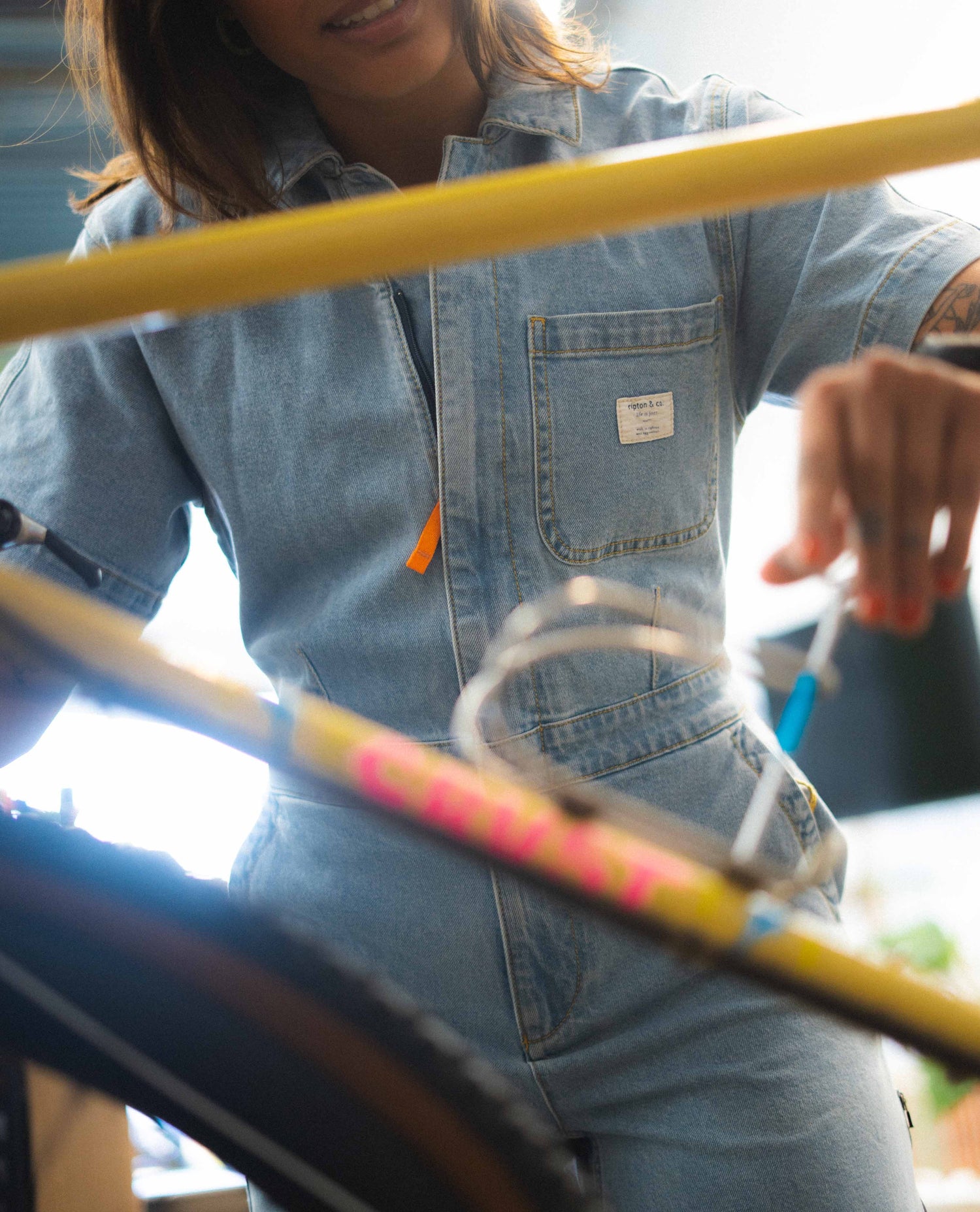 Person wearing a denim jacket with a visible brand logo, holding a colorful hula hoop.