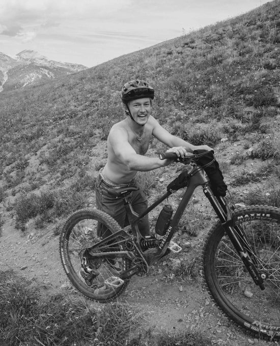 Billy riding a mountain bike on a trail with mountains in the background