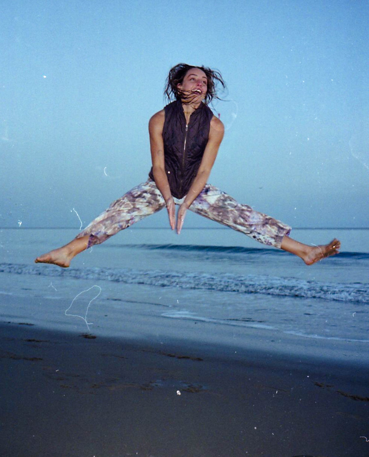 Nina jumping in Fungi Pants on beach