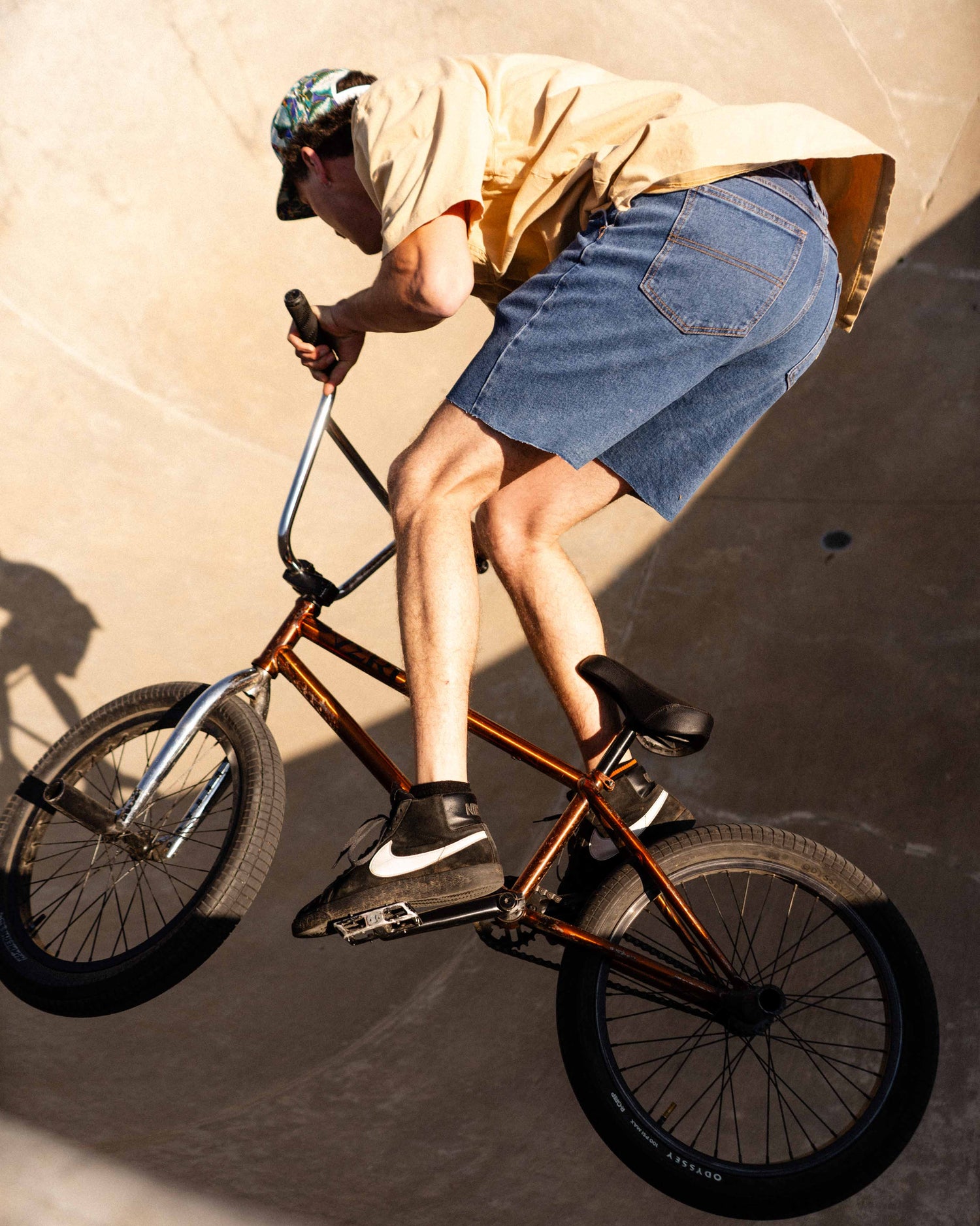 Man riding a bmx bike in a skatepark bowl in Ripton DTJ shorts. 