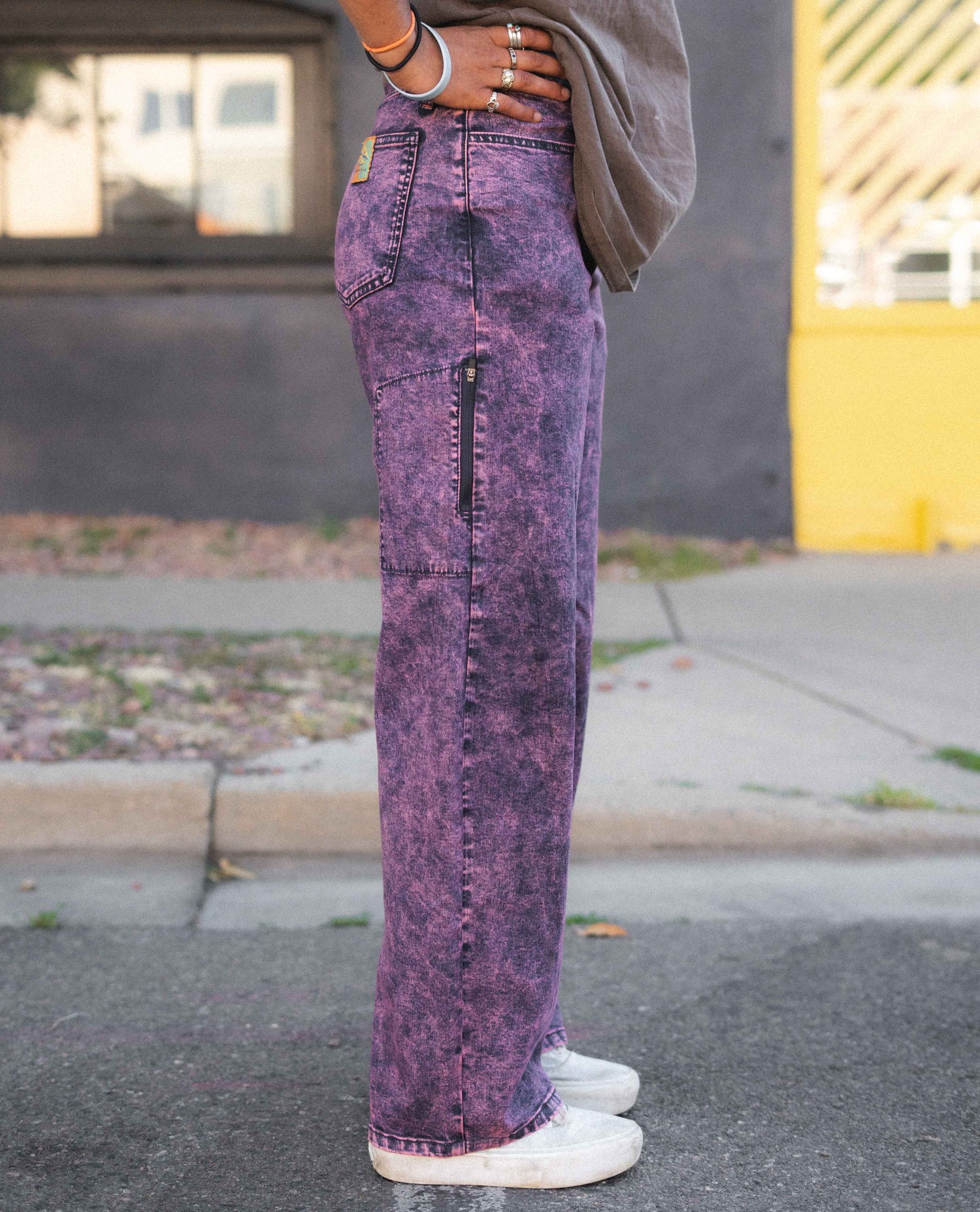 Person wearing purple acid-wash jeans on a street.