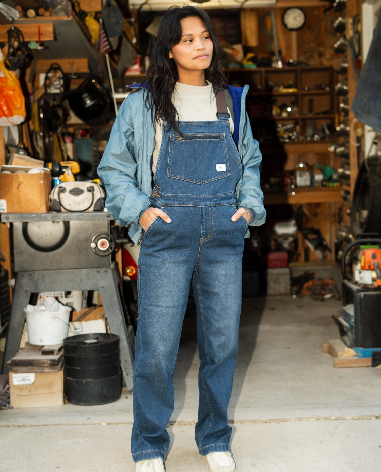 Person wearing blue denim overalls in a workshop setting
