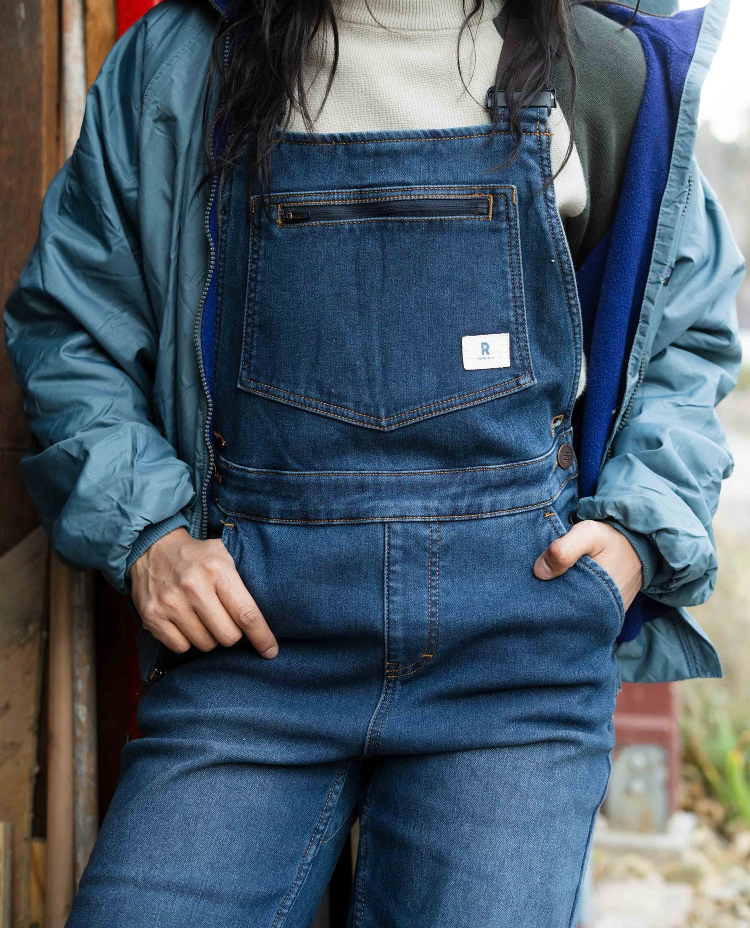 Person wearing blue denim overalls with a blurred background