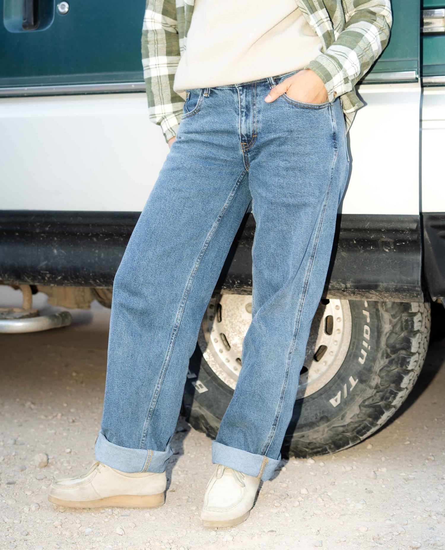 Person wearing blue jeans standing next to a vehicle