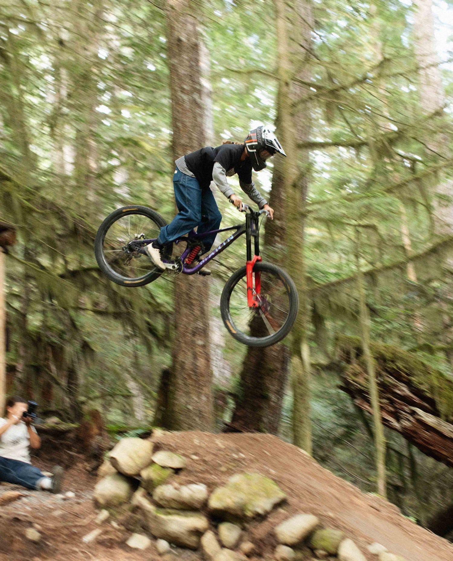 Person on a mountain bike performing a jump in a forest setting