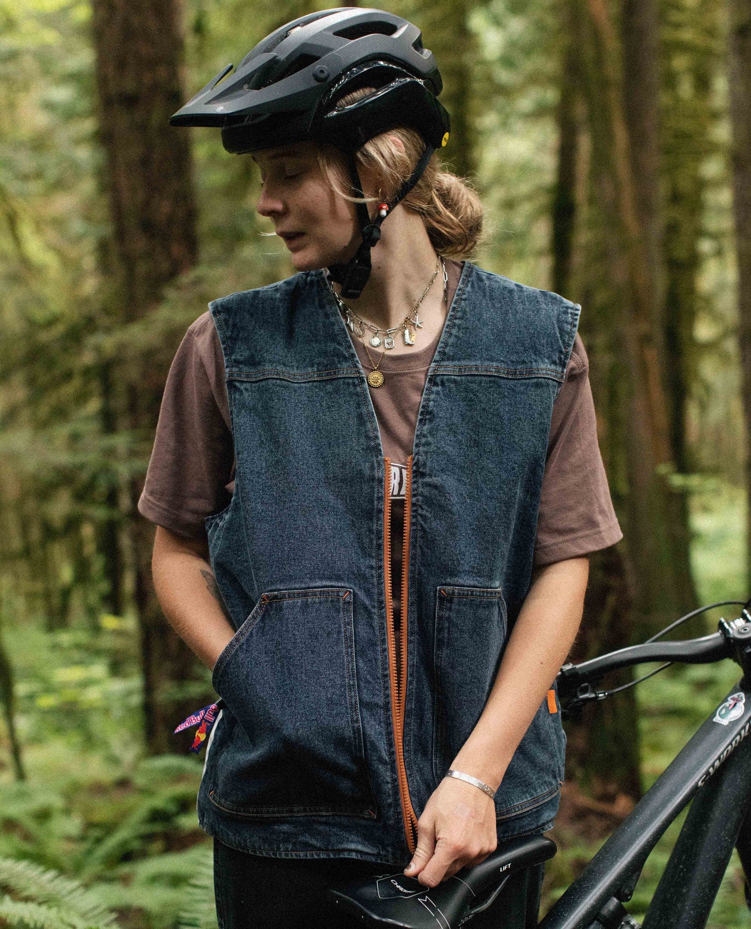 Person wearing a helmet and denim vest in a forest setting